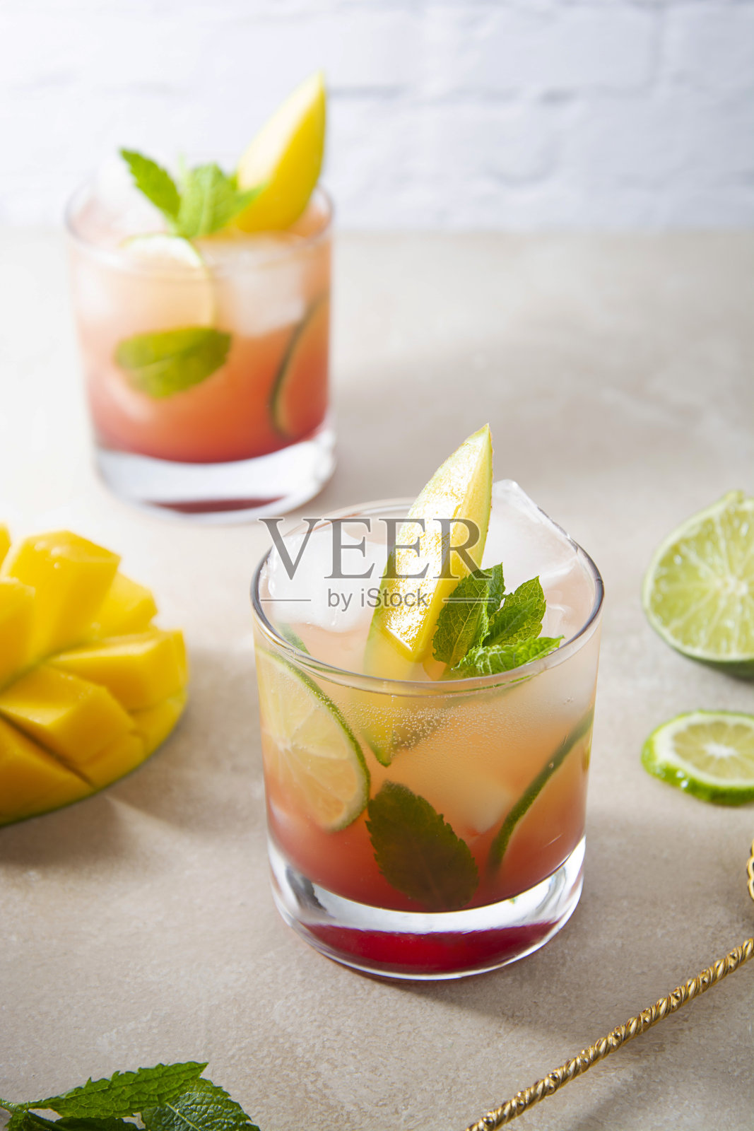 用新鲜芒果汁、冰块和薄荷叶制成的夏日芒果爽口鸡尾酒。粉色水果鸡尾酒照片摄影图片