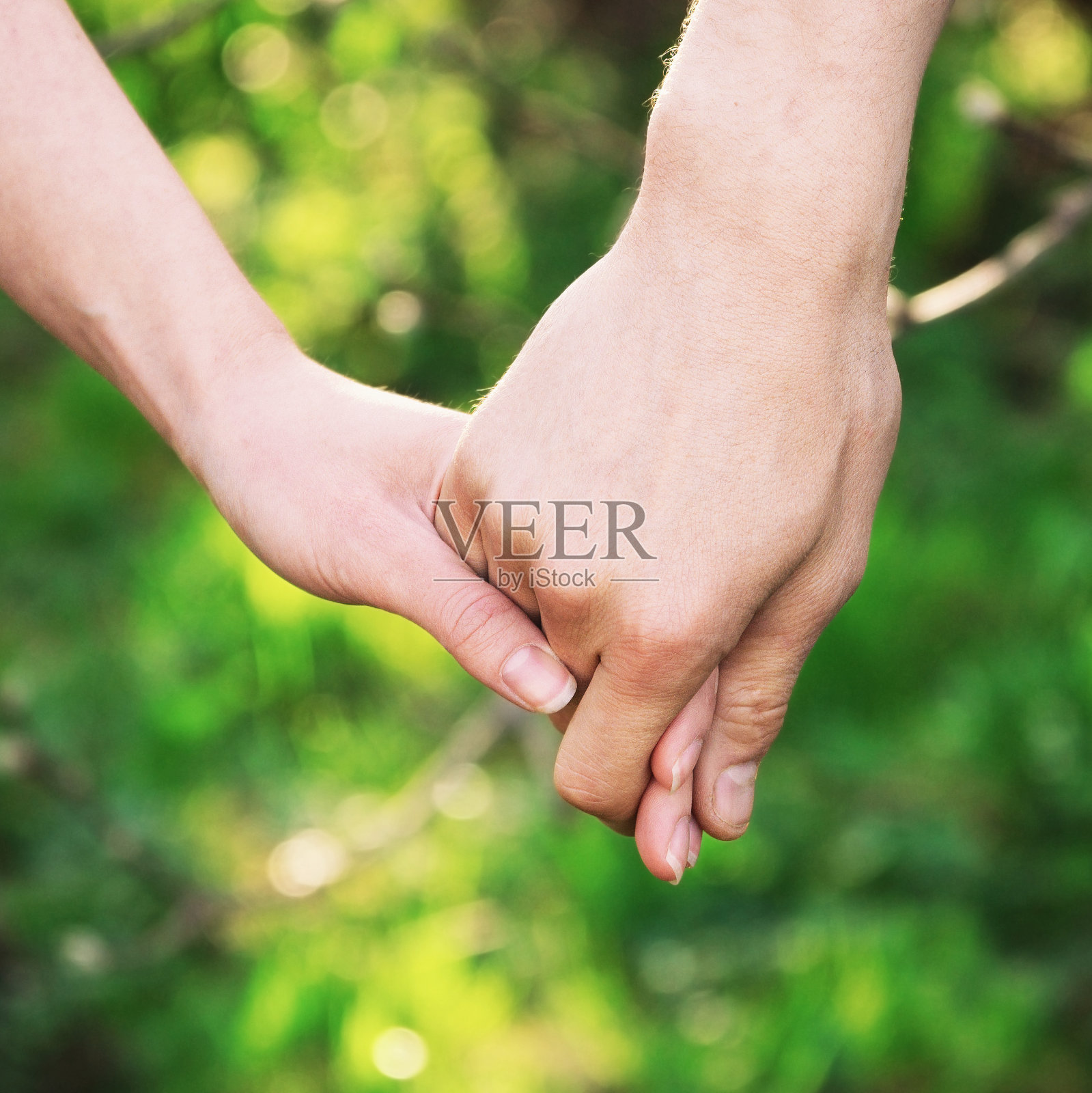 在夏季日落的户外，一对年轻夫妇的手温柔地牵着对方照片摄影图片