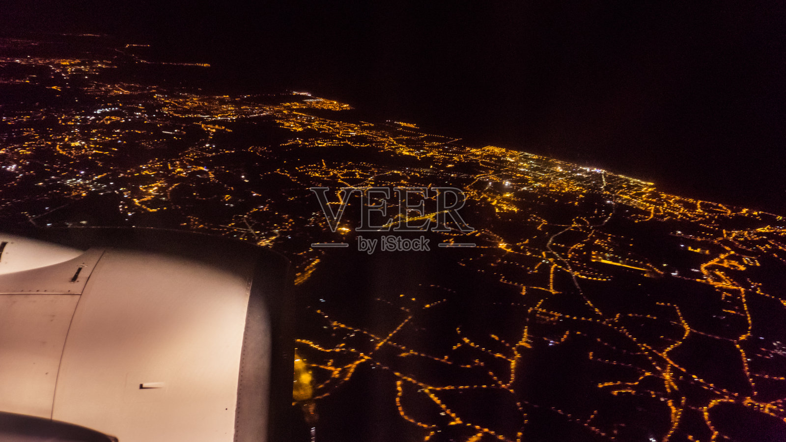 从飞机窗口鸟瞰夜晚的城市灯光和涡轮机照片摄影图片