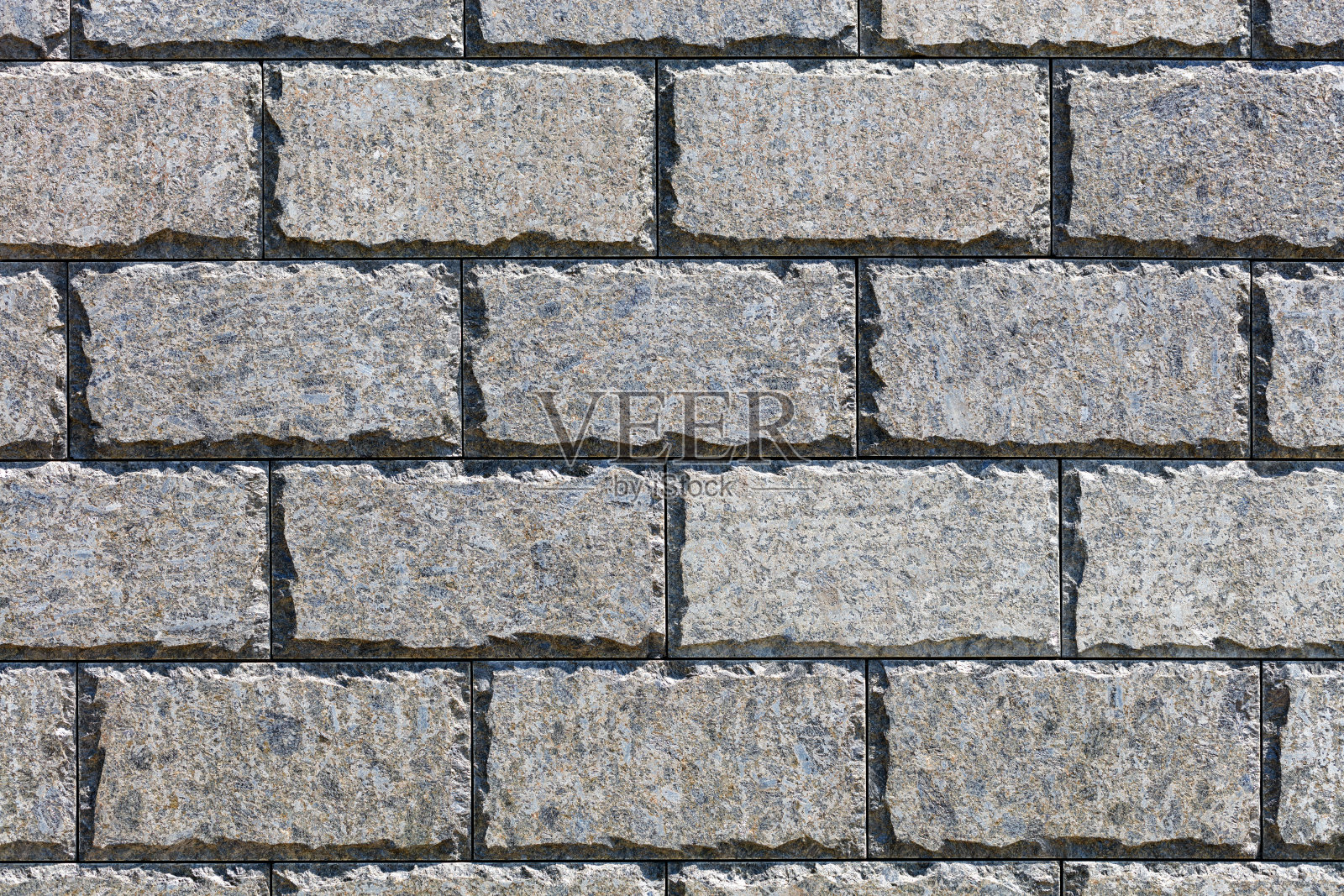 墙的美丽纹理是沿周长切割边缘的抛光石瓷砖，由阳光照射。照片摄影图片