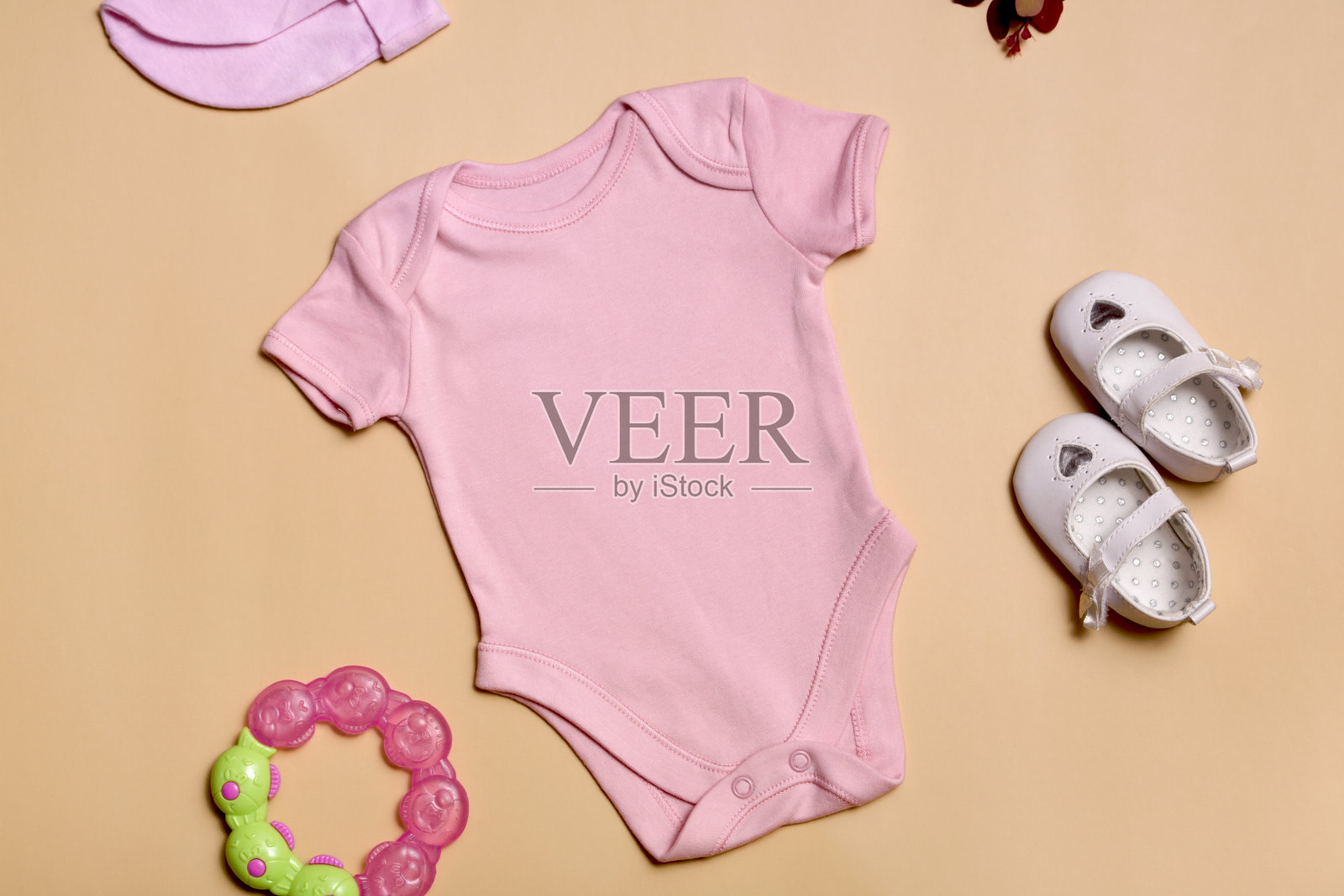 特写镜头前视图。模型空白的粉红色新生儿紧身衣的婴儿女孩米色背景，与复制空间-完美的婴儿衣服模型模板照片摄影图片