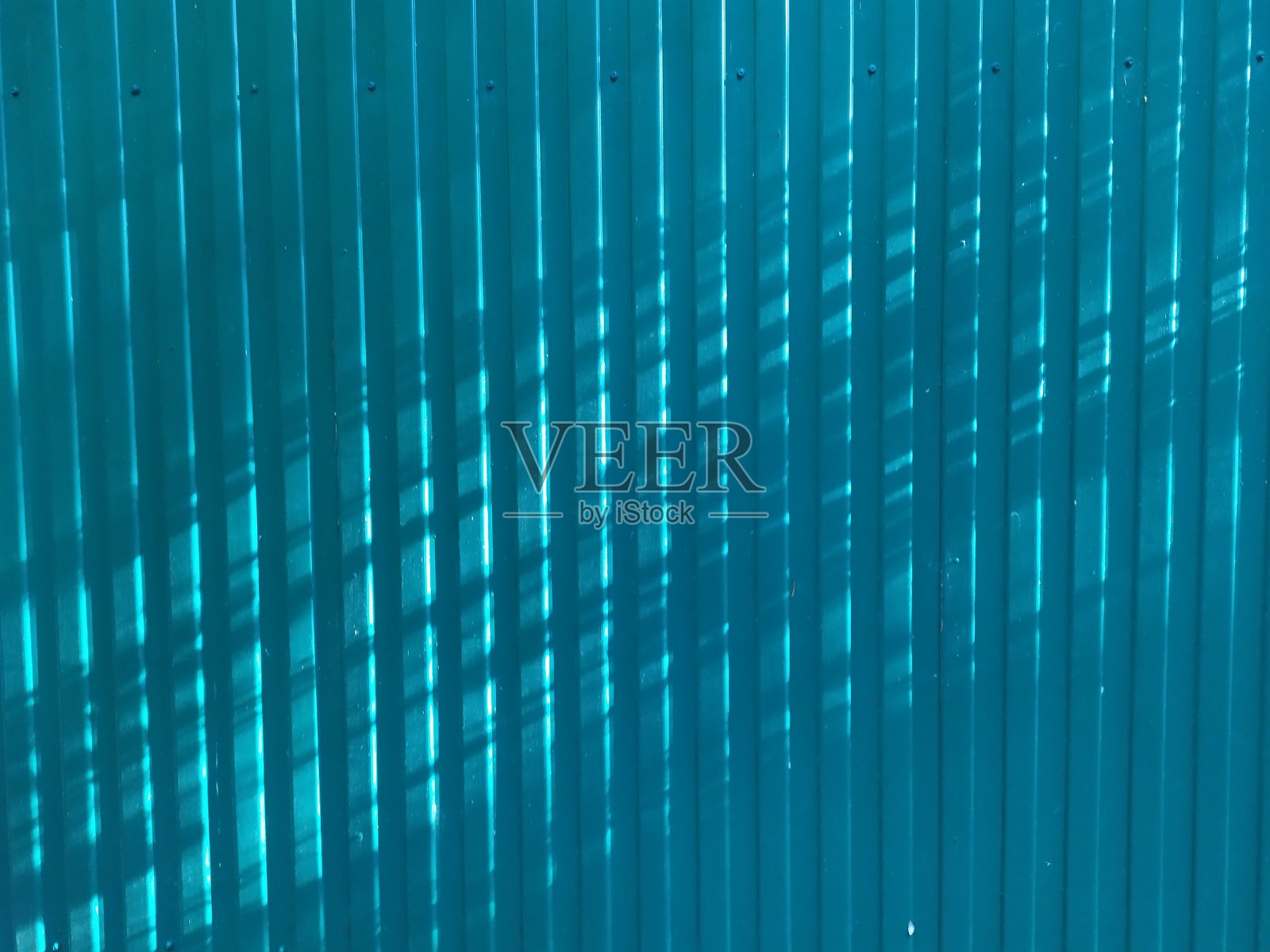 蓝色抽象背景的波纹金属栅栏在阳光下有平行和交叉的阴影照片摄影图片