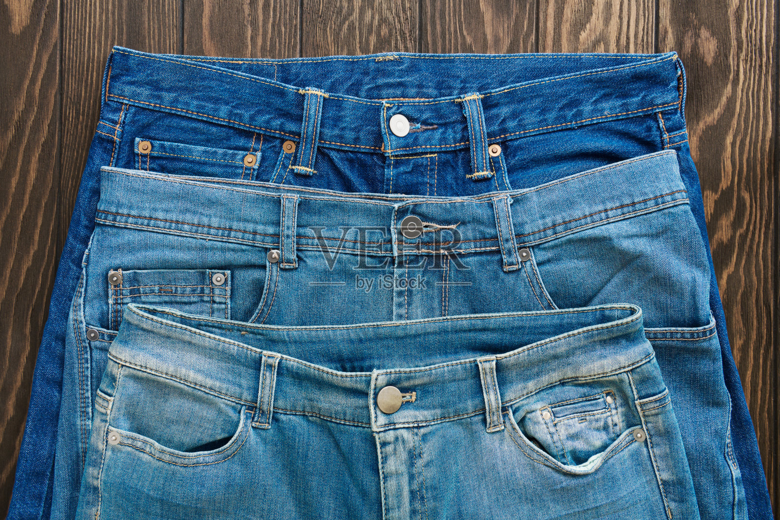 蓝色磨砂牛仔裤的接缝，扣，钮扣和铆钉，纹理，特写照片摄影图片