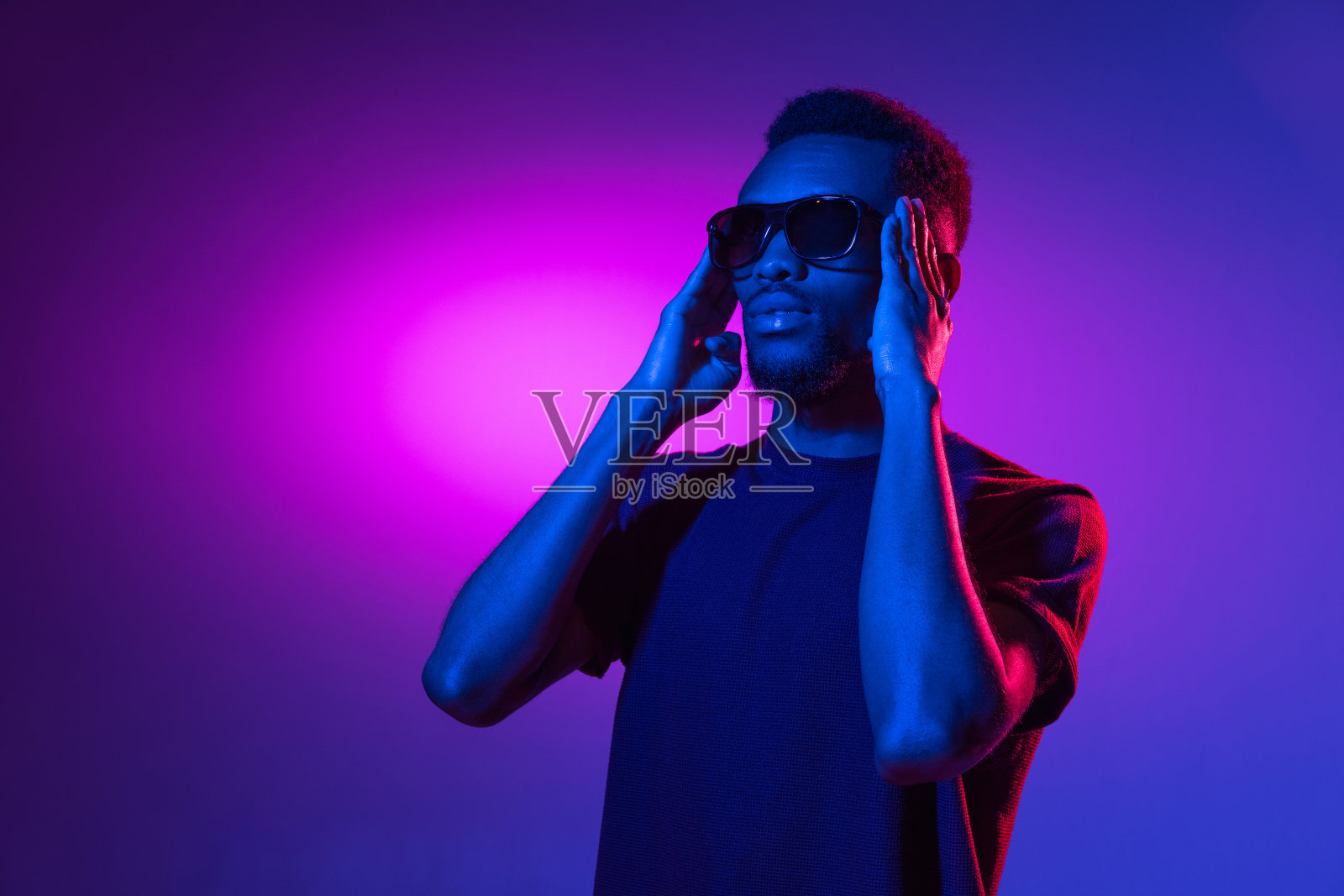 一个非洲裔美国年轻人的肖像，背景是霓虹灯。人的情感、面部表情、青春、销售、广告的概念。照片摄影图片