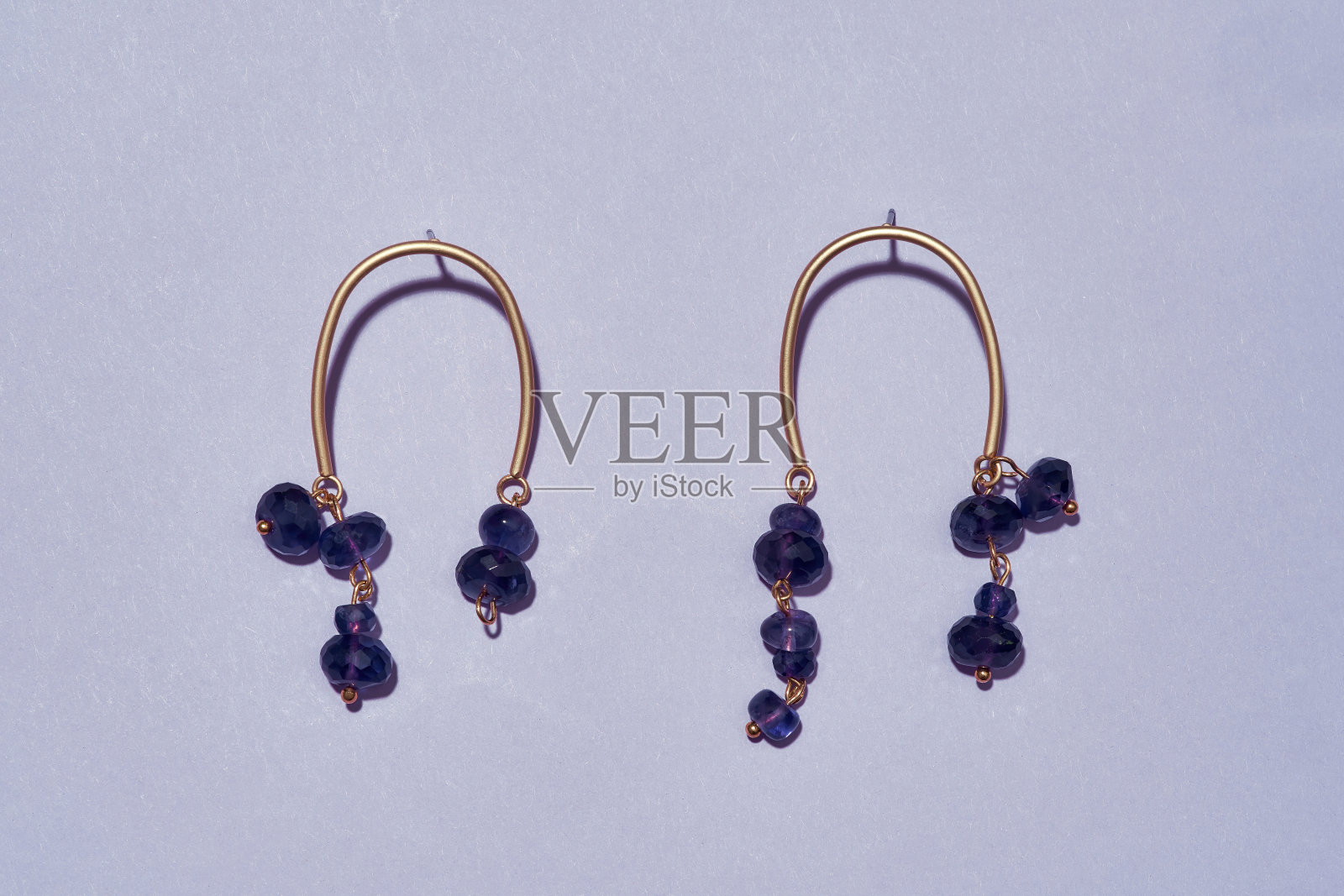 俯视图的不对称手工耳环与紫色珠子孤立在光的背景照片摄影图片