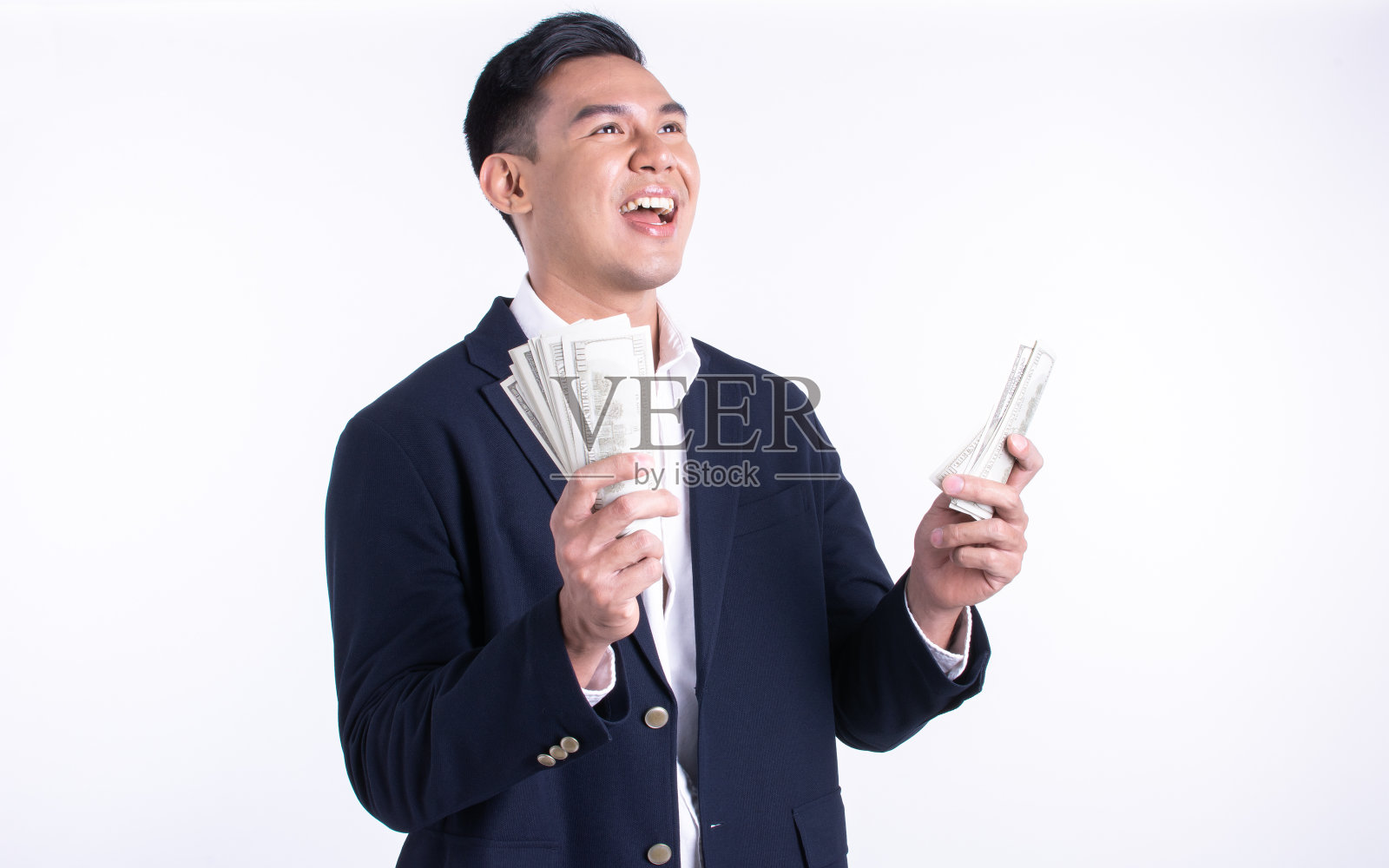 亚洲年轻的商人拿着钱，脸上带着快乐照片摄影图片