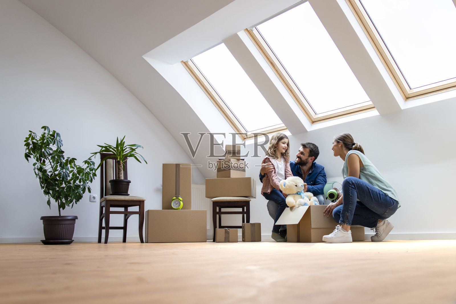 快乐的现代家庭搬到新房子，一起拆箱子。照片摄影图片