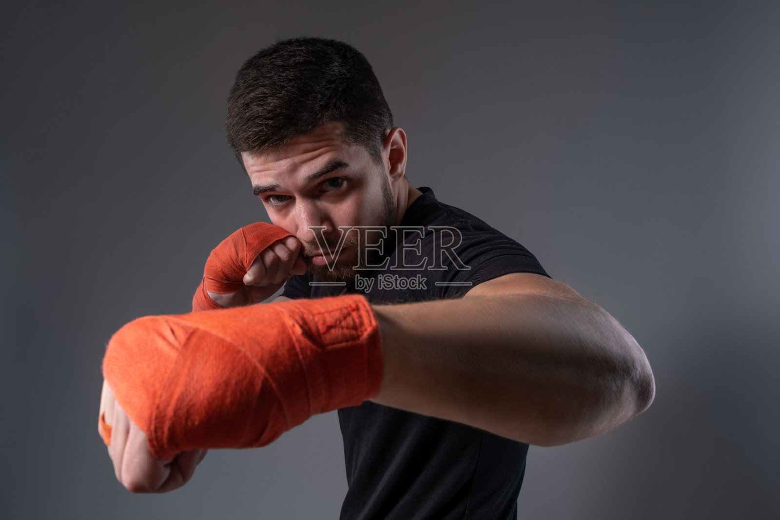 年轻的拳击手用手裹着拳击胶带表演左刺拳照片摄影图片