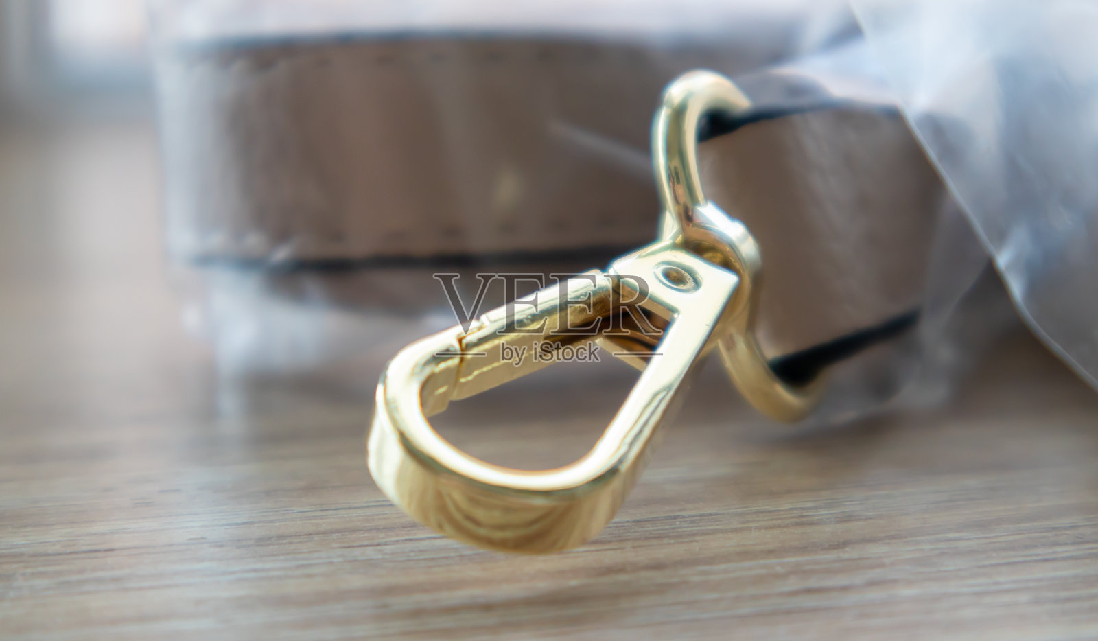 旋转扣与皮革米黄色袋皮带在一个木制的背景。带旋转夹或钩的金属钩环。小黄金配件近距离选择焦点照片摄影图片