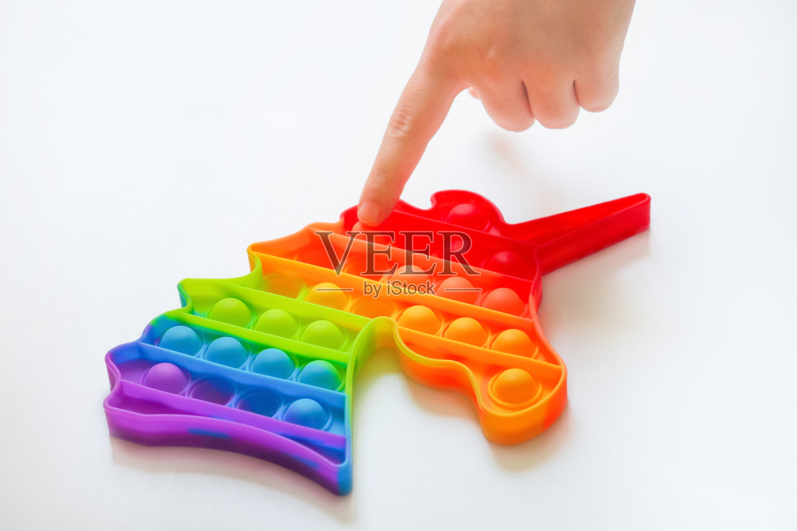 时髦的流行玩具它以独角兽的形式坐立不安。感官抗压爆它的玩具，彩虹色照片摄影图片