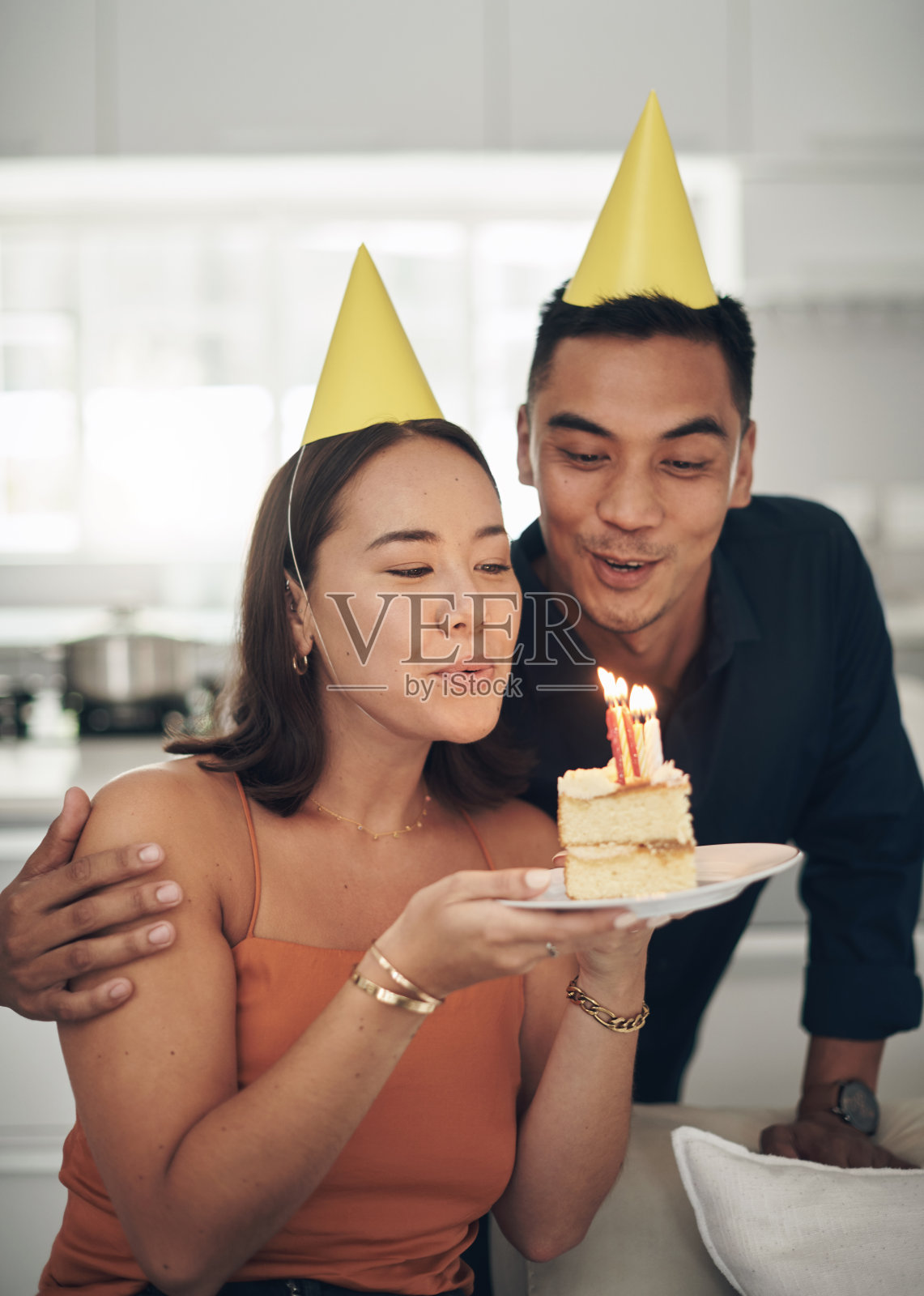 一对年轻夫妇在家里吹灭蛋糕上的蜡烛照片摄影图片