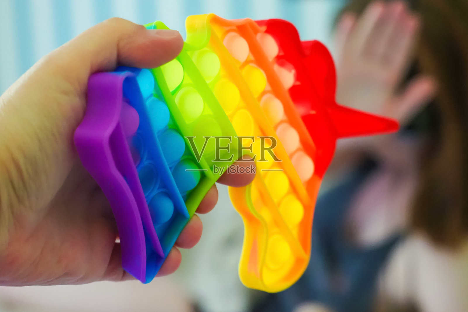 孩子拒绝时髦的玩具。时髦的玩具把它做成独角兽的形状。感官抗压爆它的玩具，彩虹色照片摄影图片