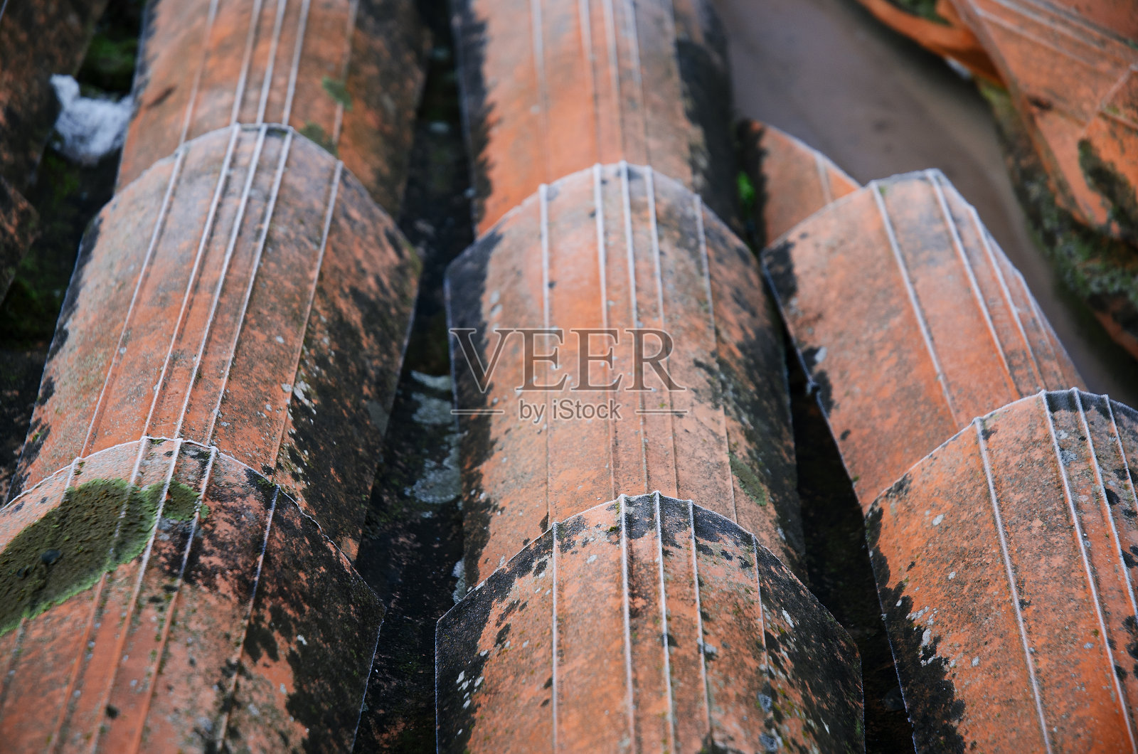 旧的霜冻屋顶瓦片碎片。房子的屋顶，旧风化的肮脏的红色瓦片靠近。复古瓷砖作为背景。照片摄影图片