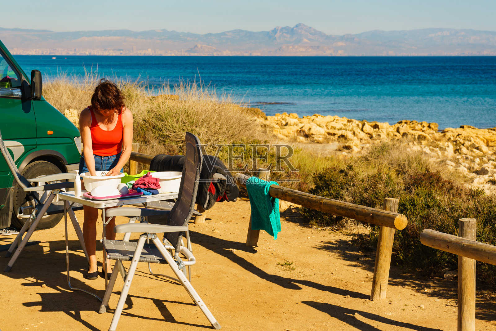 女人在碗里洗盘子，帐篷在室外照片摄影图片