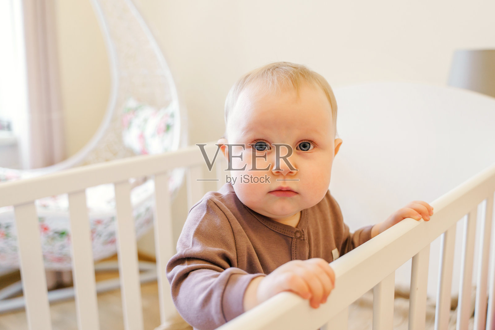 在明亮的房间里，一个可爱的婴儿抱着婴儿床照片摄影图片