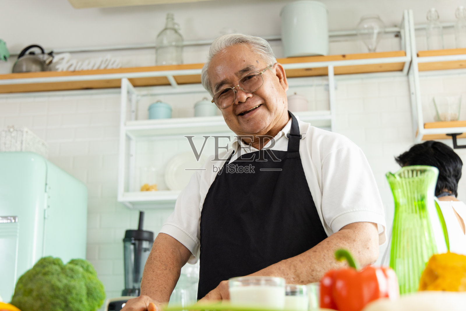一个年长的亚洲夫妇在家庭厨房做饭的肖像。他们有一个微笑的脸和高兴的活动。退休人员通过选择健康的食物来照顾自己。照片摄影图片