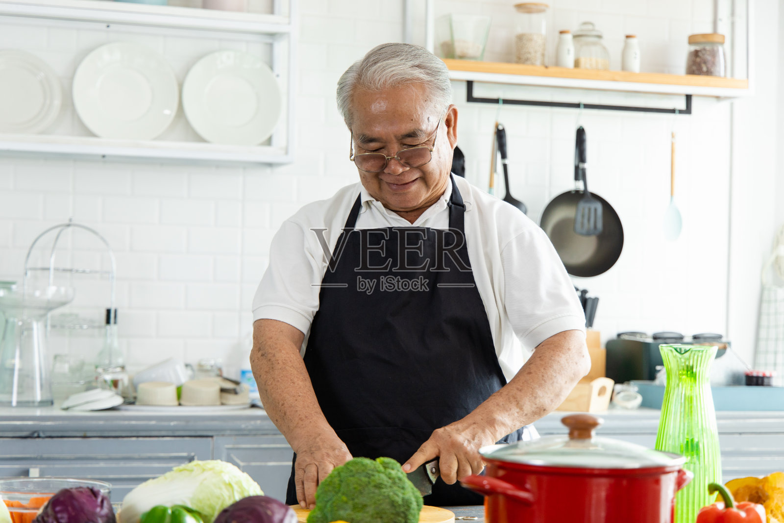 亚洲老人在家庭厨房做饭的肖像。他们有一个微笑的脸和高兴的活动。退休人员通过选择健康的食物来照顾自己。照片摄影图片
