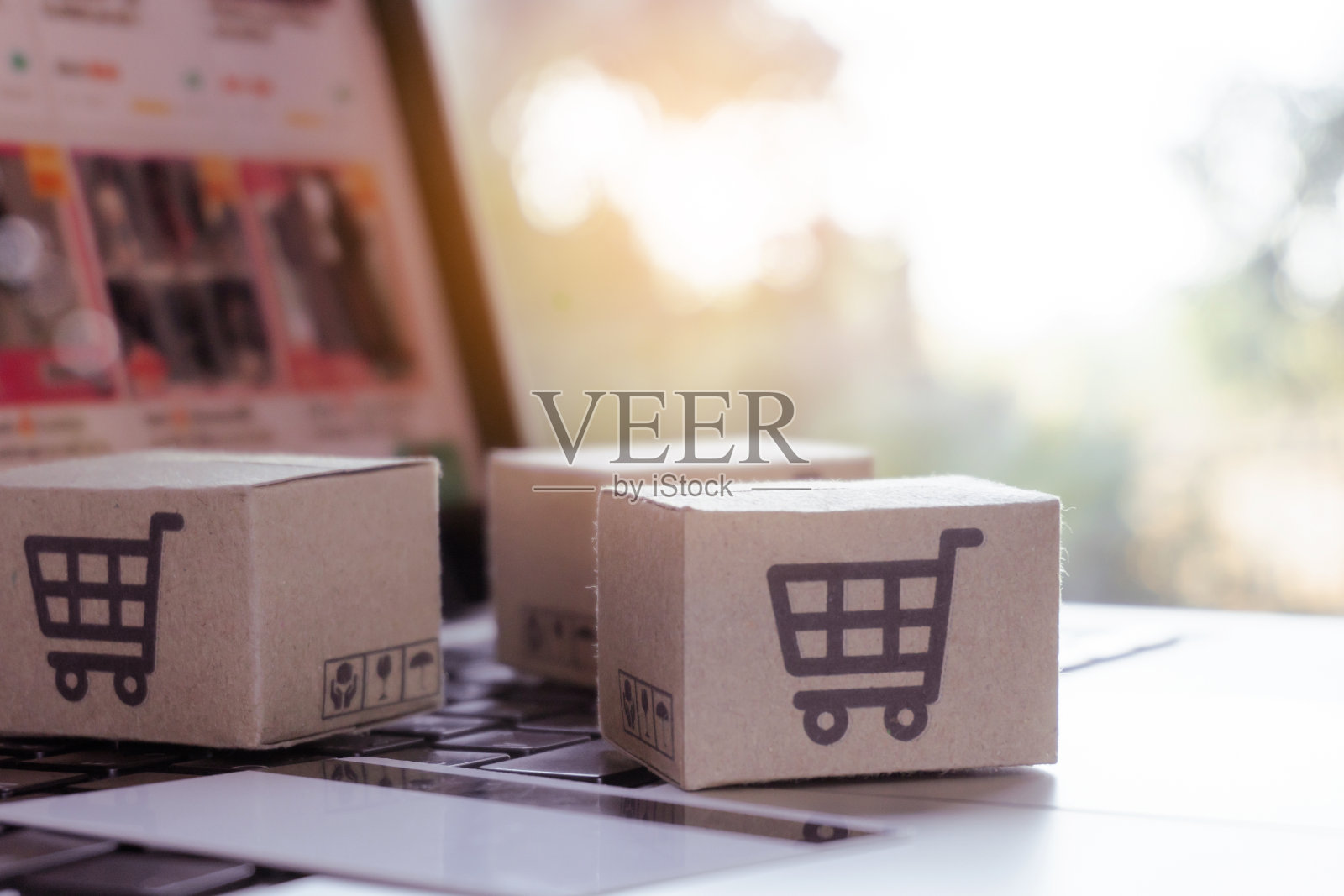 在线购物。信用卡和纸板箱，电脑键盘上有一个购物车的标志。网上购物服务。提供送货上门照片摄影图片