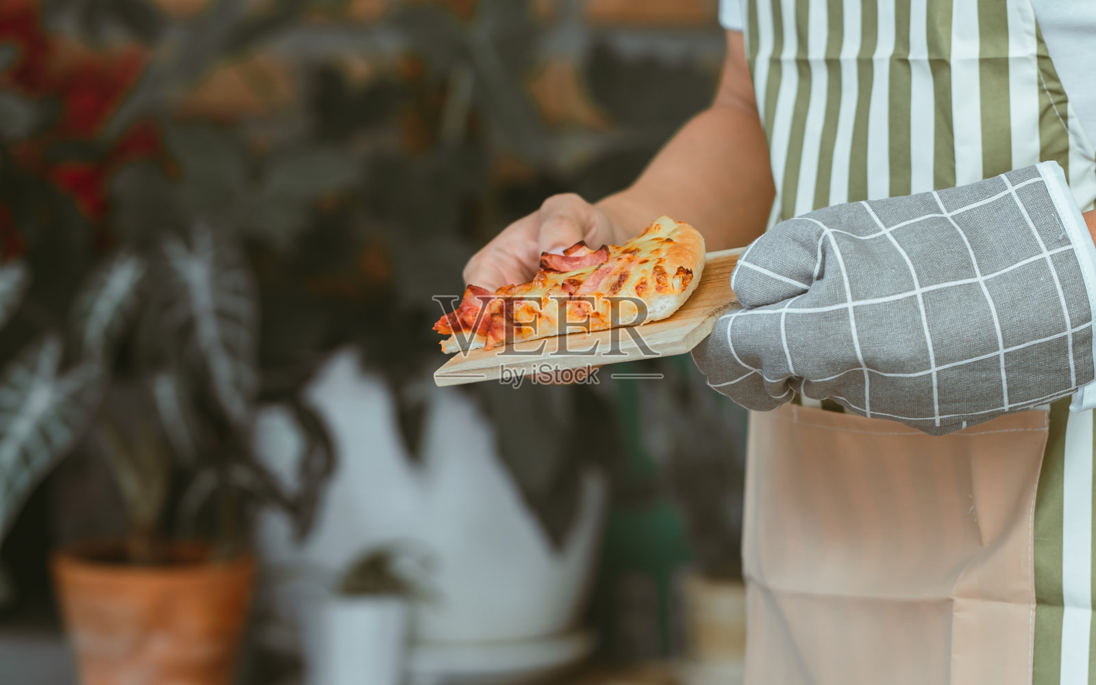 在厨房里，离拿着披萨的男人的手很近照片摄影图片