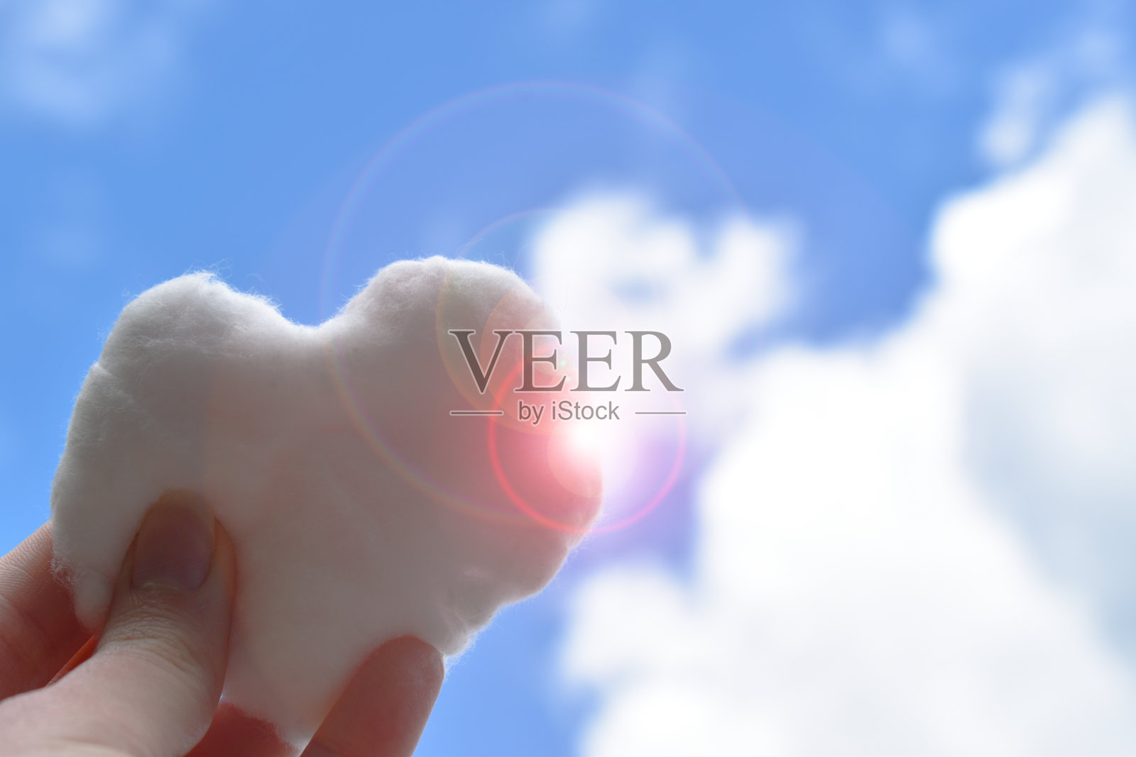人的手捧着一颗心形的云，在阳光照耀的天空中照片摄影图片