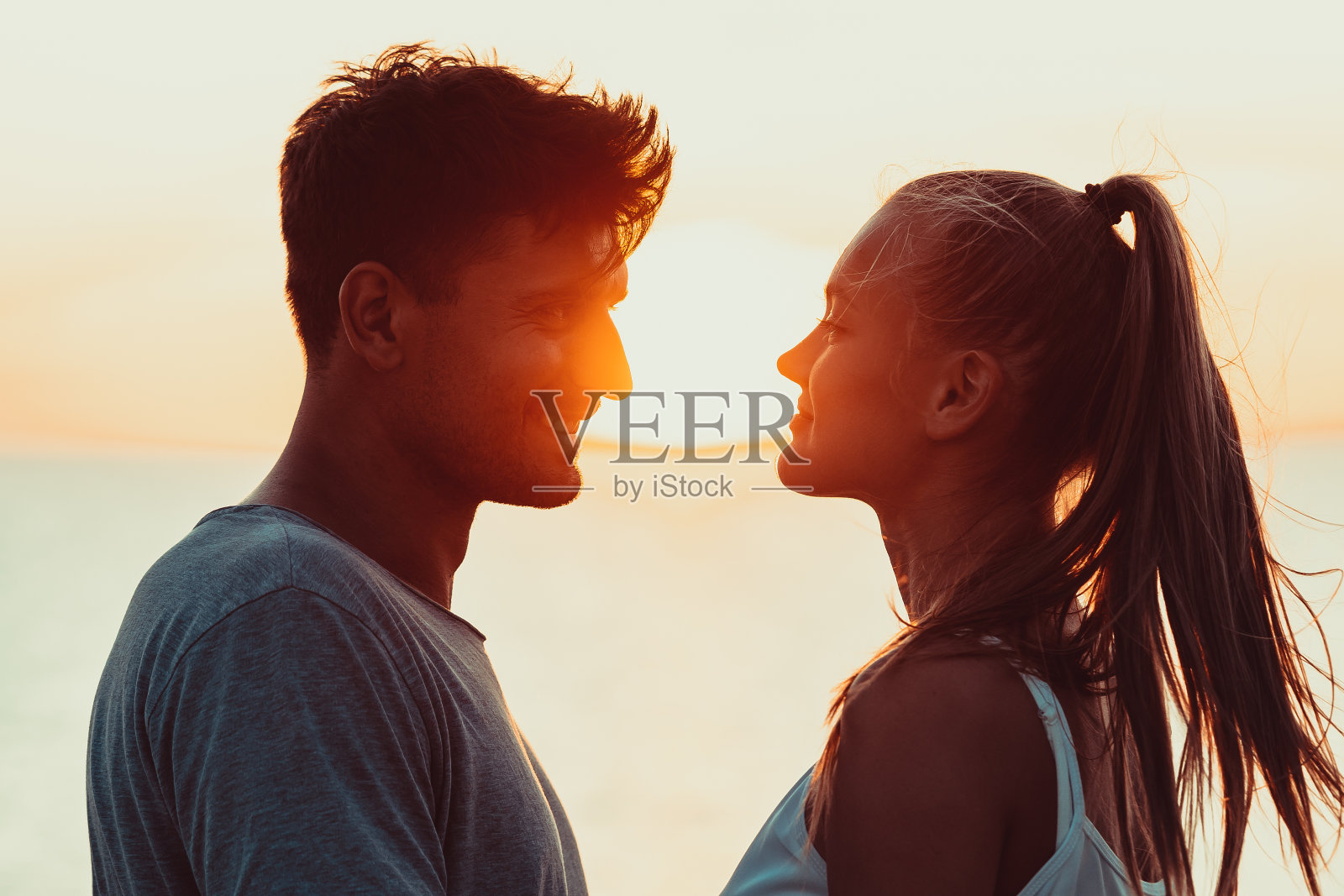 这对浪漫的情侣紧紧地站在美丽的日落背景上照片摄影图片