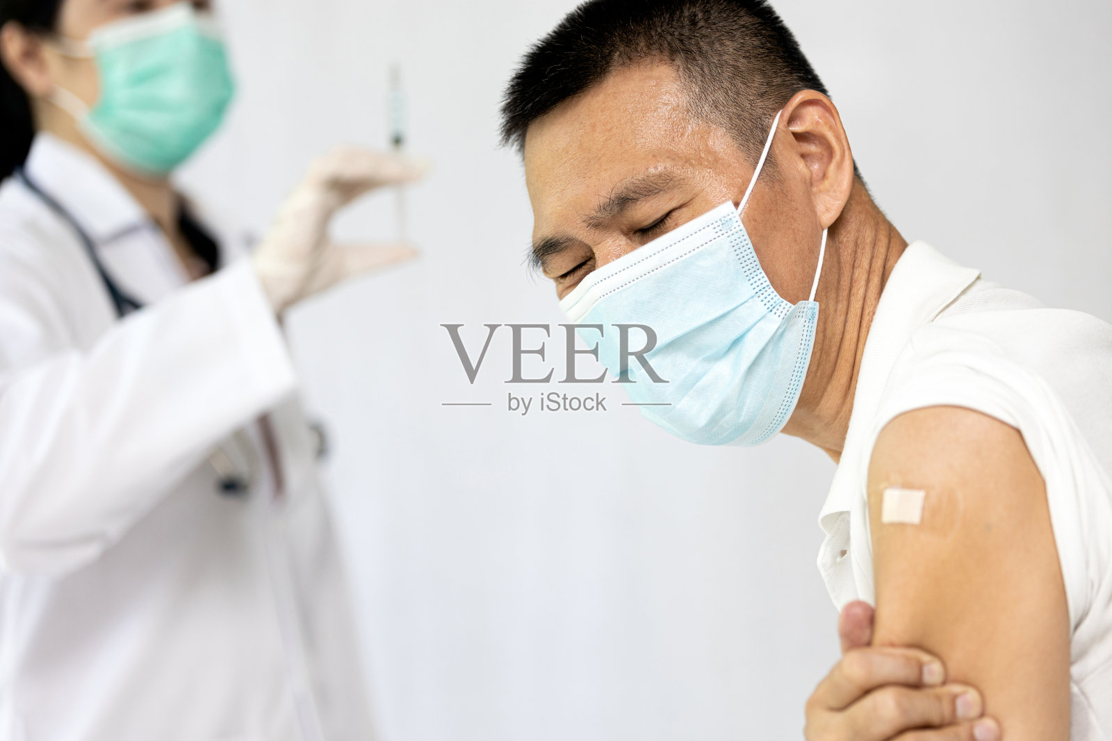 生病期间拒绝接种，患病的中年男子首次注射冠状病毒疫苗后出现发烧、肩痛、准备接受第二剂COVID-19疫苗照片摄影图片