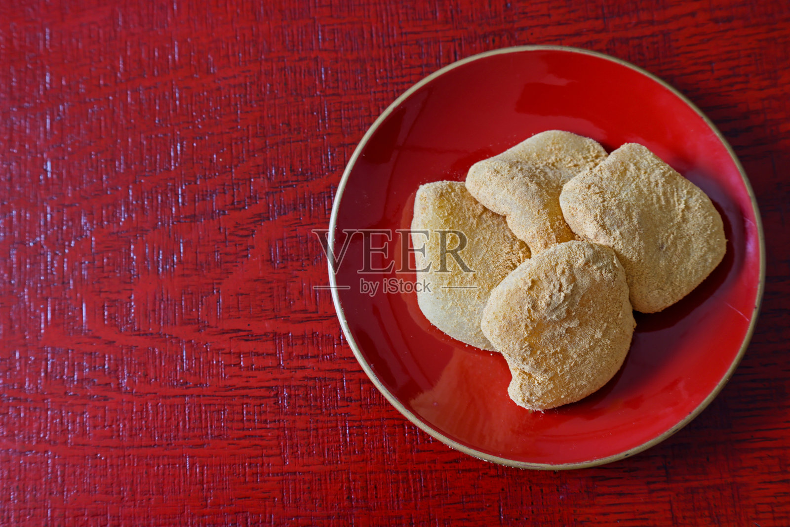 红漆器上的一种煮年糕，上面覆盖着甜黄豆粉。照片摄影图片