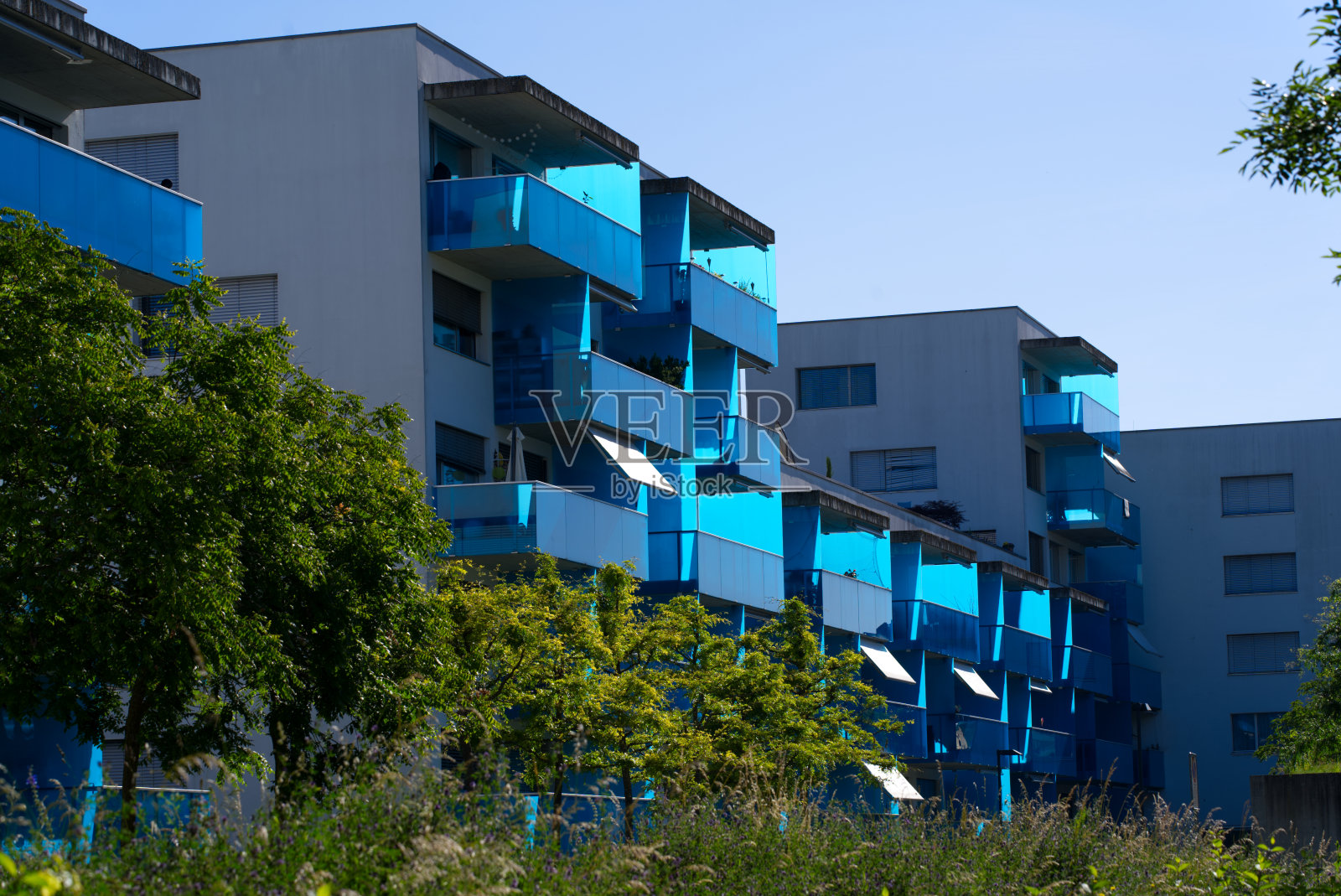 苏黎世Schlieren公寓大楼，在一个阳光明媚的夏天早晨，有时尚的蓝色阳台。照片摄影图片