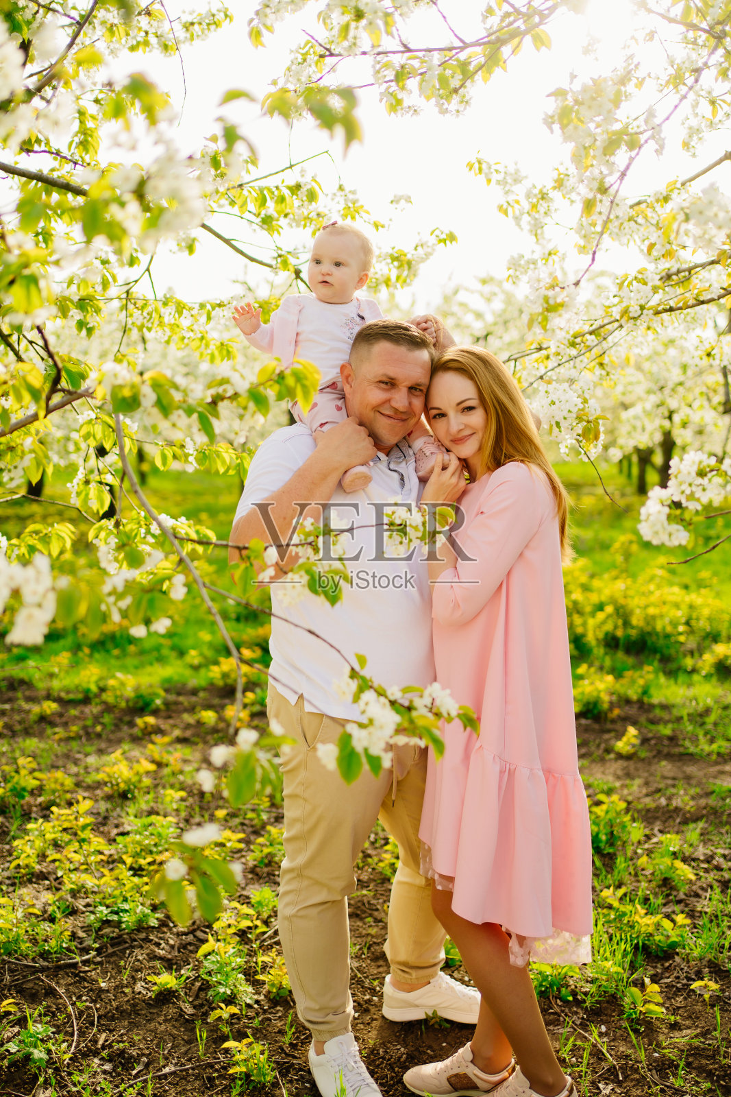 妈妈、爸爸、女儿在春暖花开的花园里。婴儿唇裂。照片摄影图片