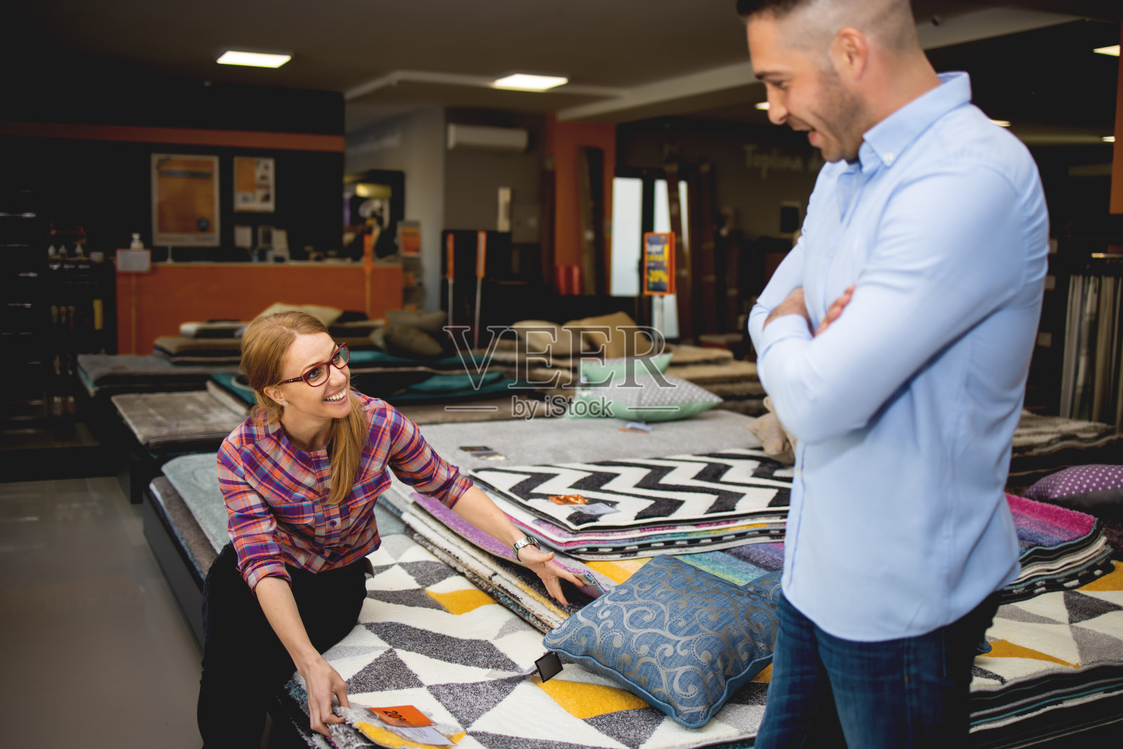 一对年轻夫妇在家具店买地毯。照片摄影图片