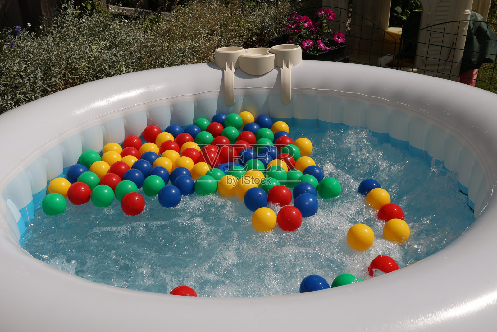 五颜六色的球漂浮在充气池里冒泡的水中照片摄影图片