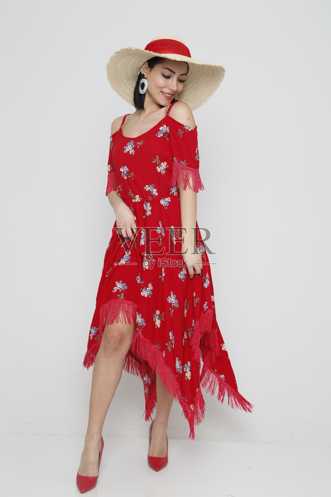 年轻漂亮的女人穿着红色的夏装，戴着白色背景的帽子。照片摄影图片
