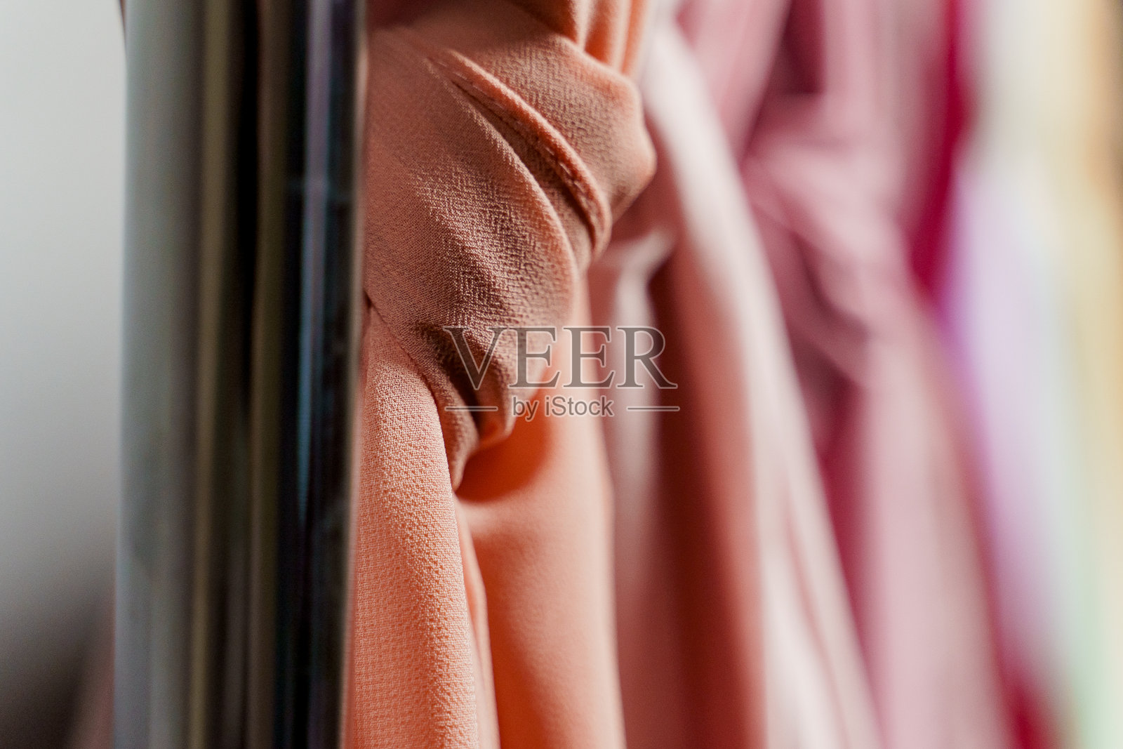 丝绸围巾穆斯林特写。多色素色围巾挂在衣架上。照片摄影图片