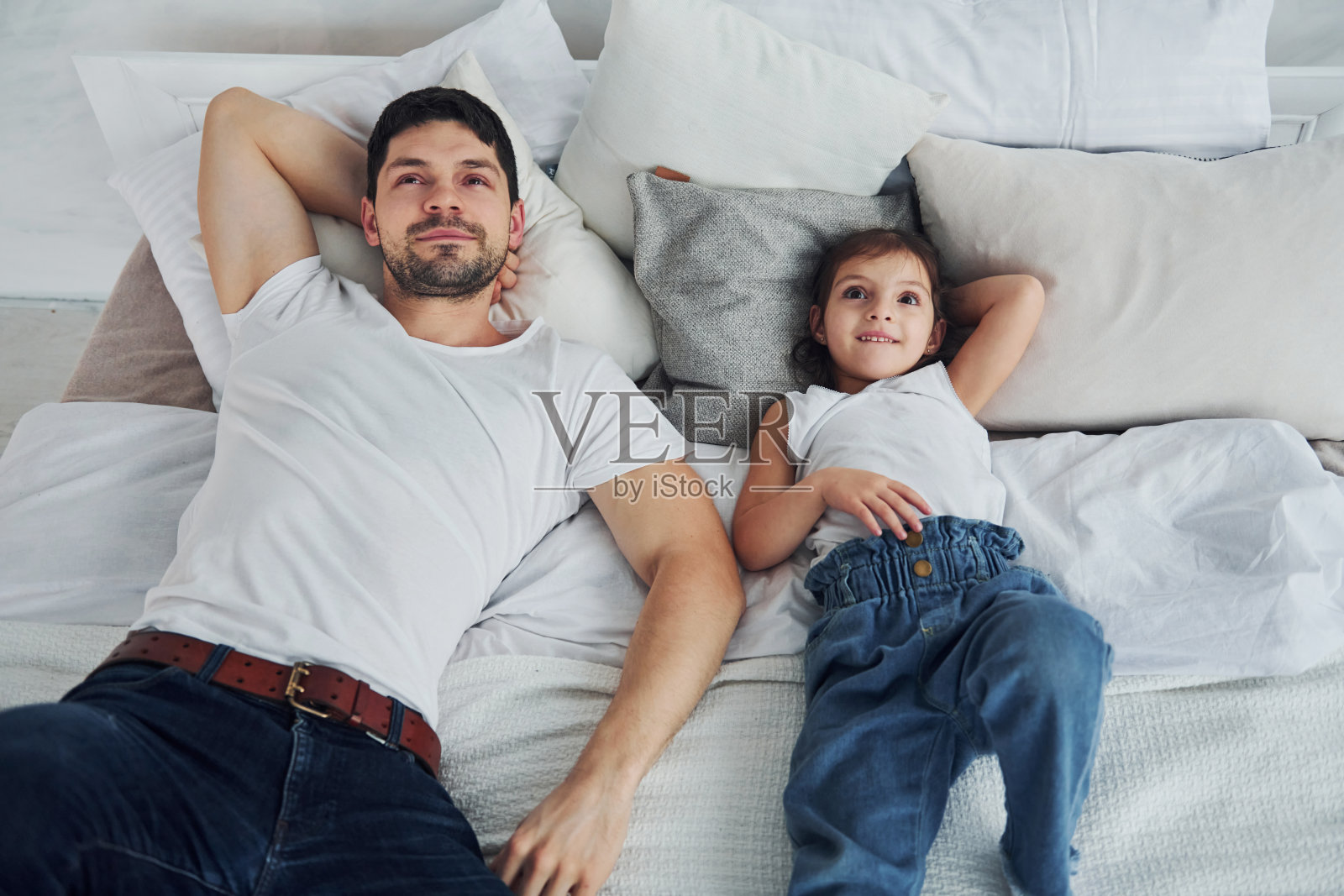 快乐的父亲和他的女儿一起在家里度过空闲时间。躺在床上照片摄影图片