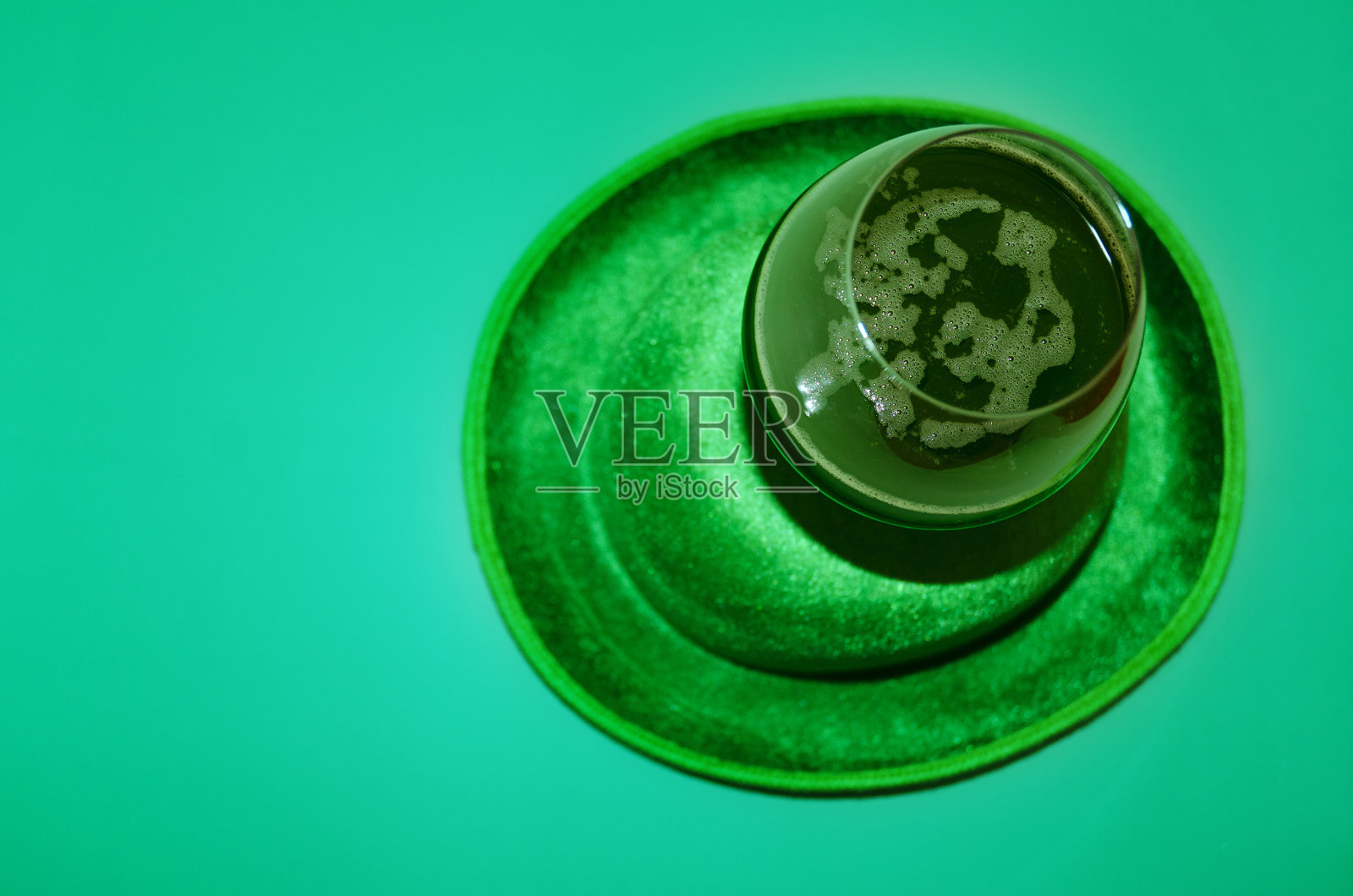 圣帕特里克节快乐。一杯绿色啤酒。派对眼镜和帽子在绿色背景。贺卡。副本的空间。前视图。照片摄影图片