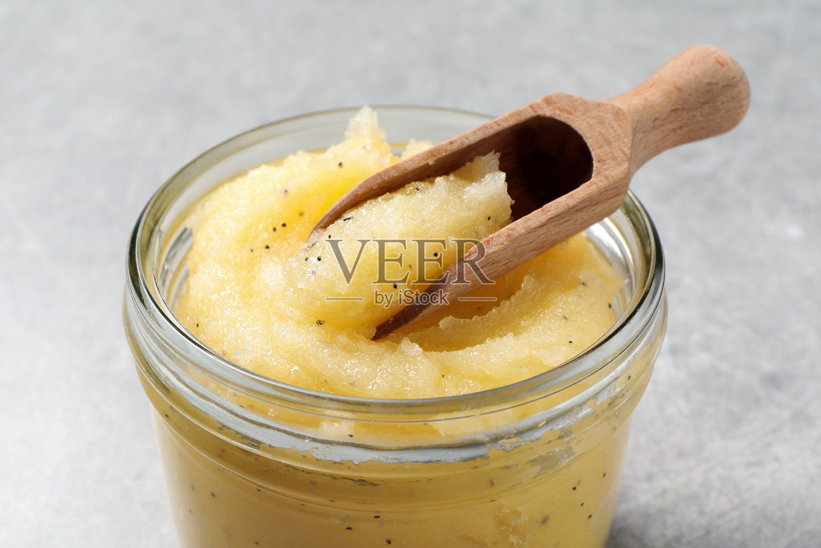 特写镜头，用玻璃罐舀的身体磨砂膏，浅灰色背景照片摄影图片