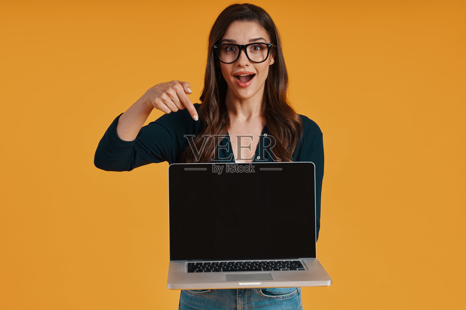 快乐的年轻女子在智能休闲服装指向拷贝空间的笔记本电脑照片摄影图片