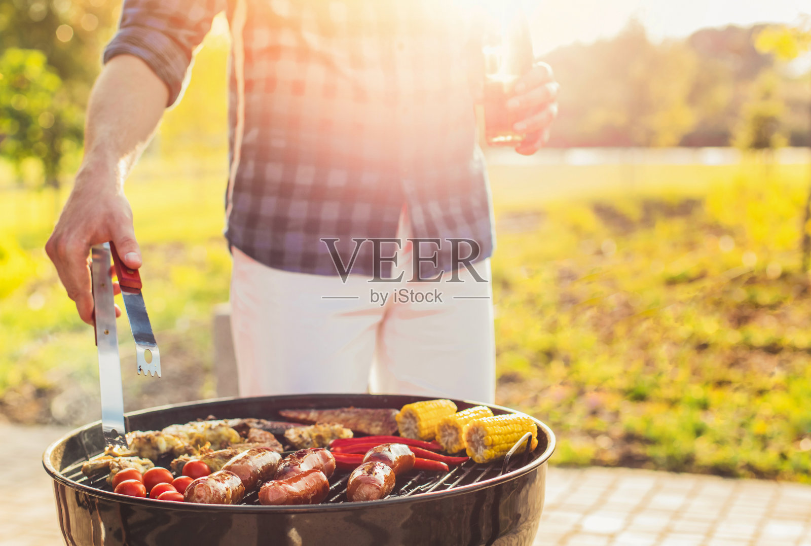 美味的什锦烤肉和香肠，配以烤制蔬菜，带着烟和火焰在户外的公园里照片摄影图片
