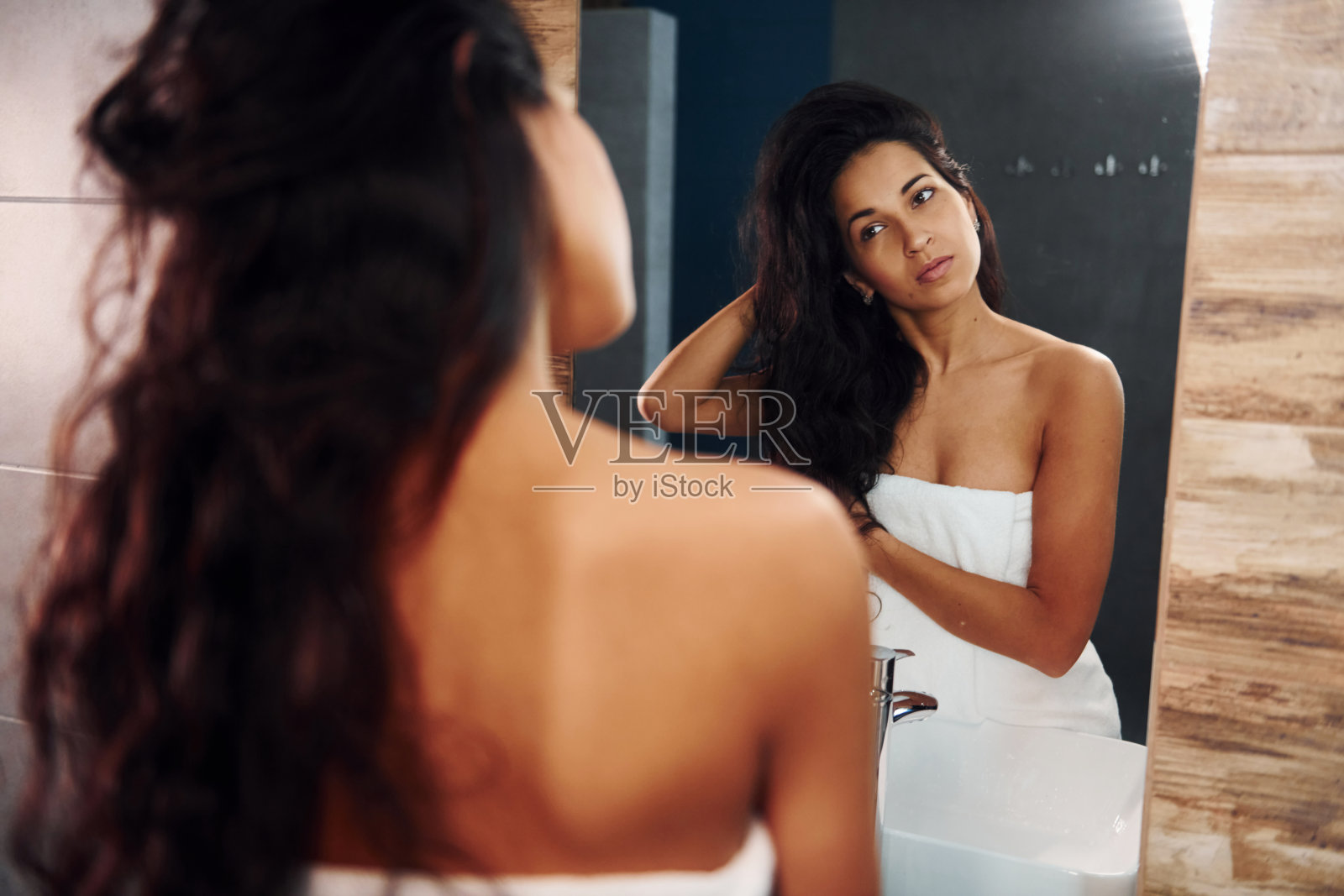 漂亮的年轻女子站在浴室镜子旁边照片摄影图片