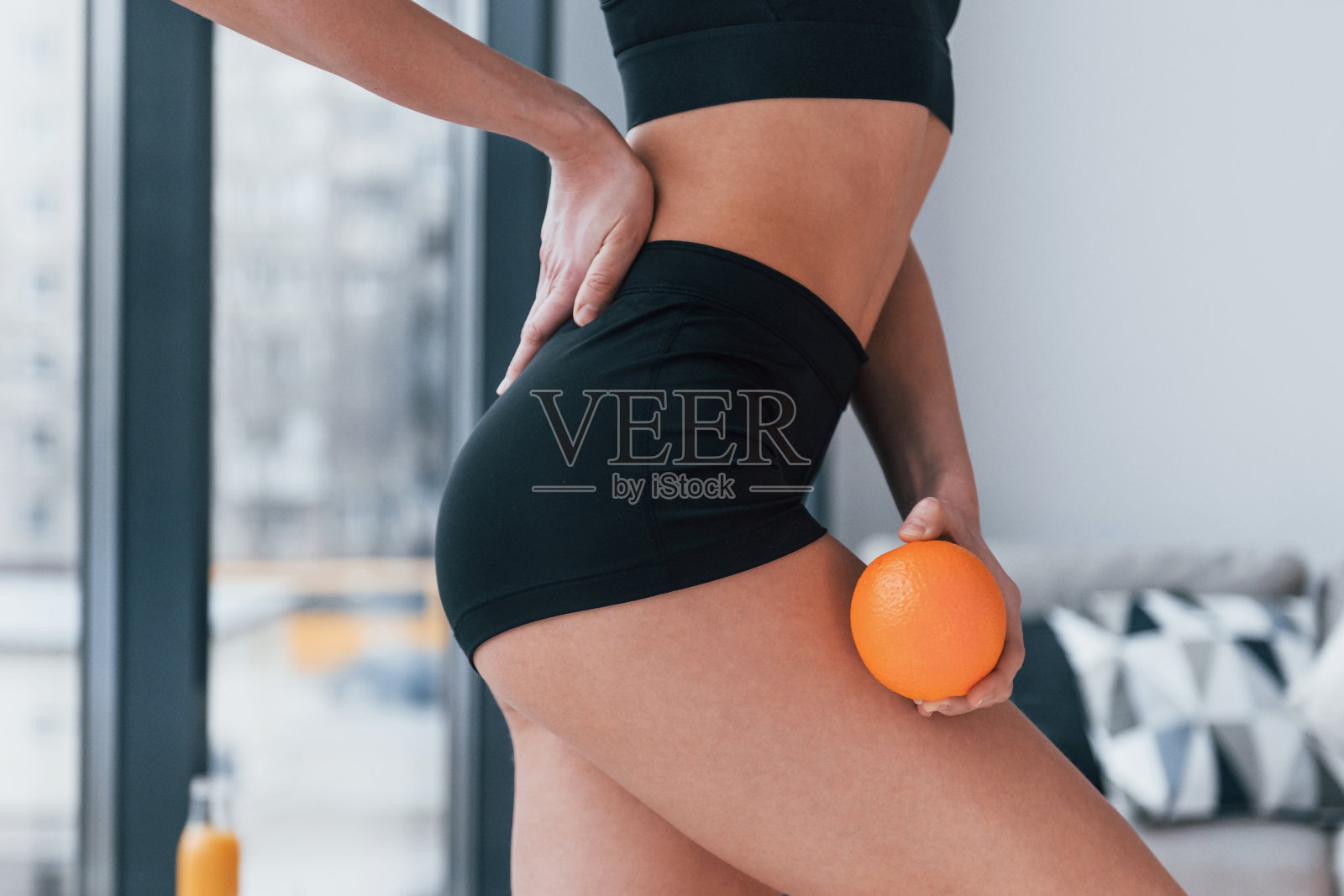 手里拿着健康的食物。身材苗条的年轻女子在黑色运动服有健身日在家照片摄影图片