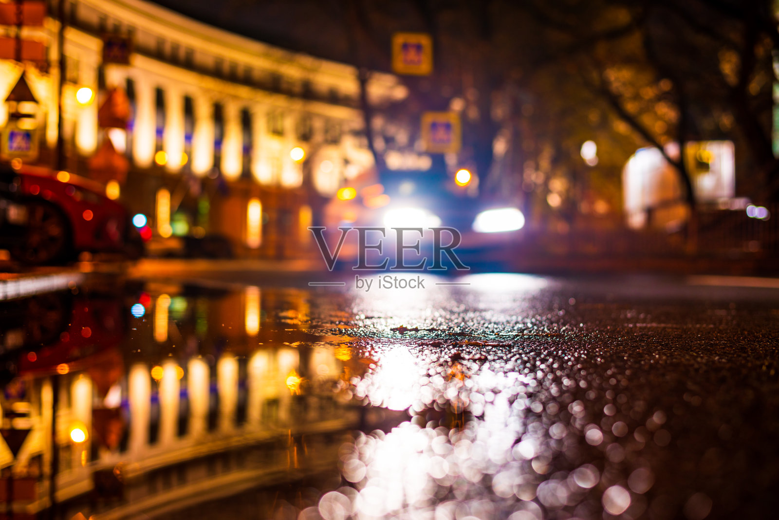 秋雨夜城。骑乘汽车的前灯。停着的汽车。市中心的住宅建筑。五彩缤纷的颜色。照片摄影图片