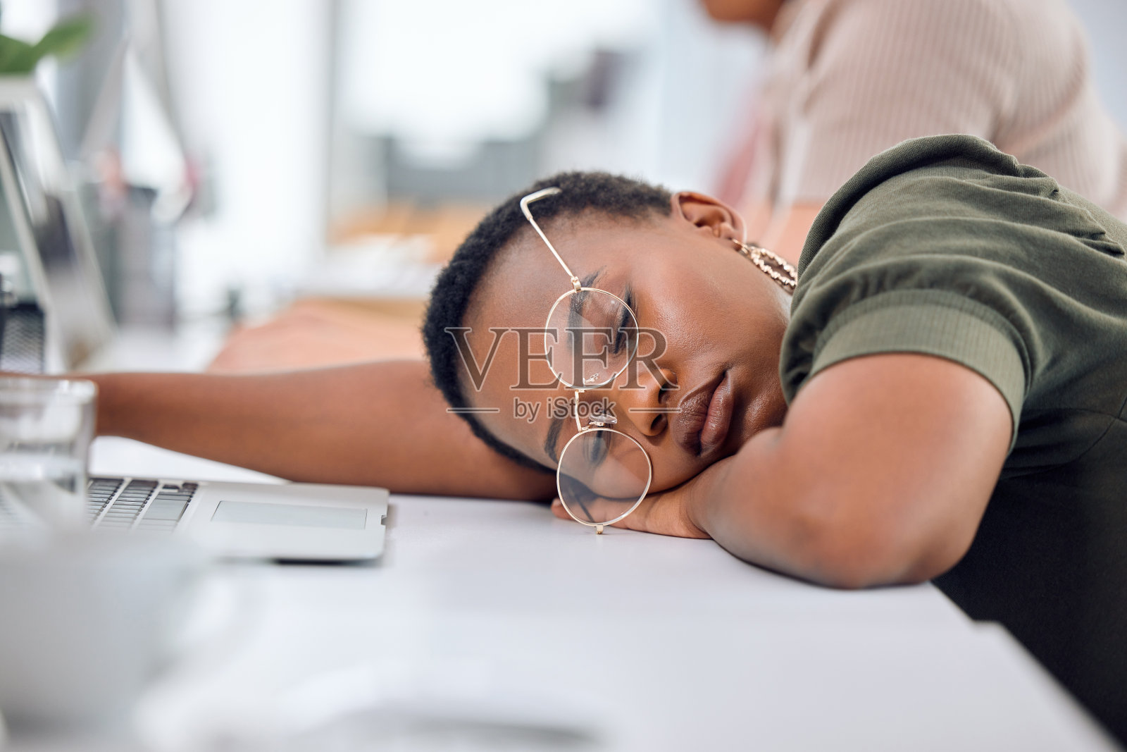 一个年轻的女商人睡在办公室的办公桌上照片摄影图片