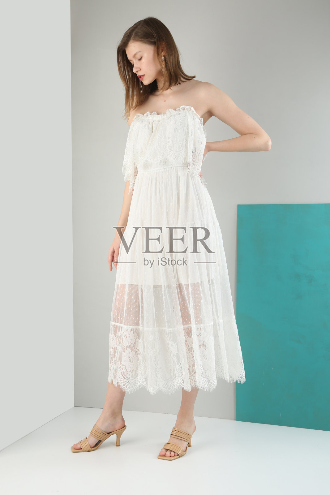 年轻漂亮的女人穿着白色的裙子，前面是白色的背景。照片摄影图片