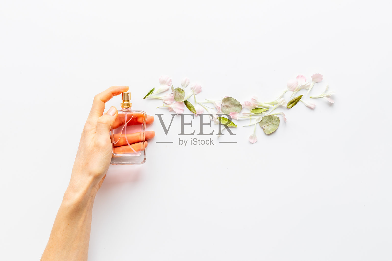 女性手喷香水瓶和流动的鲜花照片摄影图片