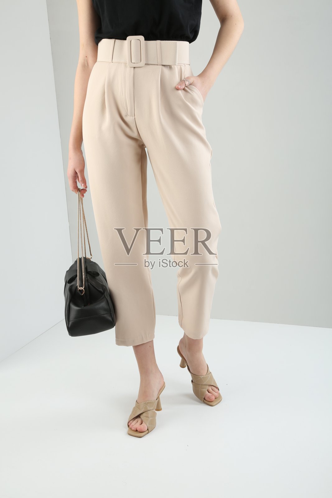 年轻漂亮的女人穿着黑色t恤和裤子前面的白色背景。照片摄影图片