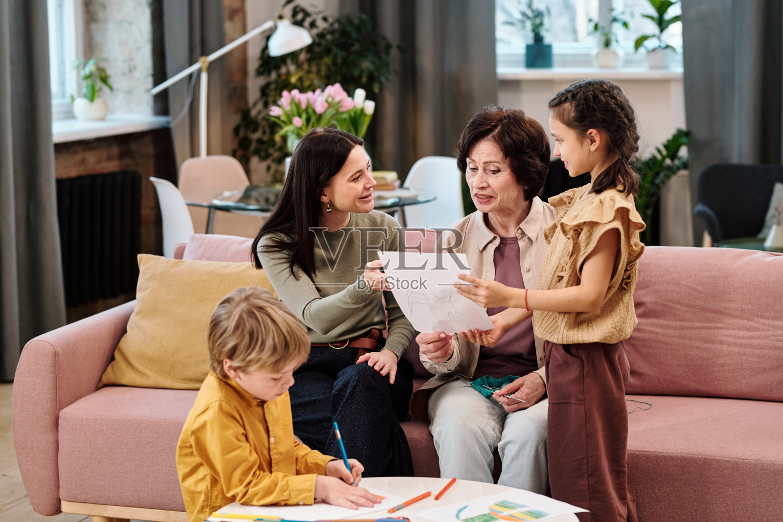 可爱的女孩向妈妈和奶奶展示她的画照片摄影图片