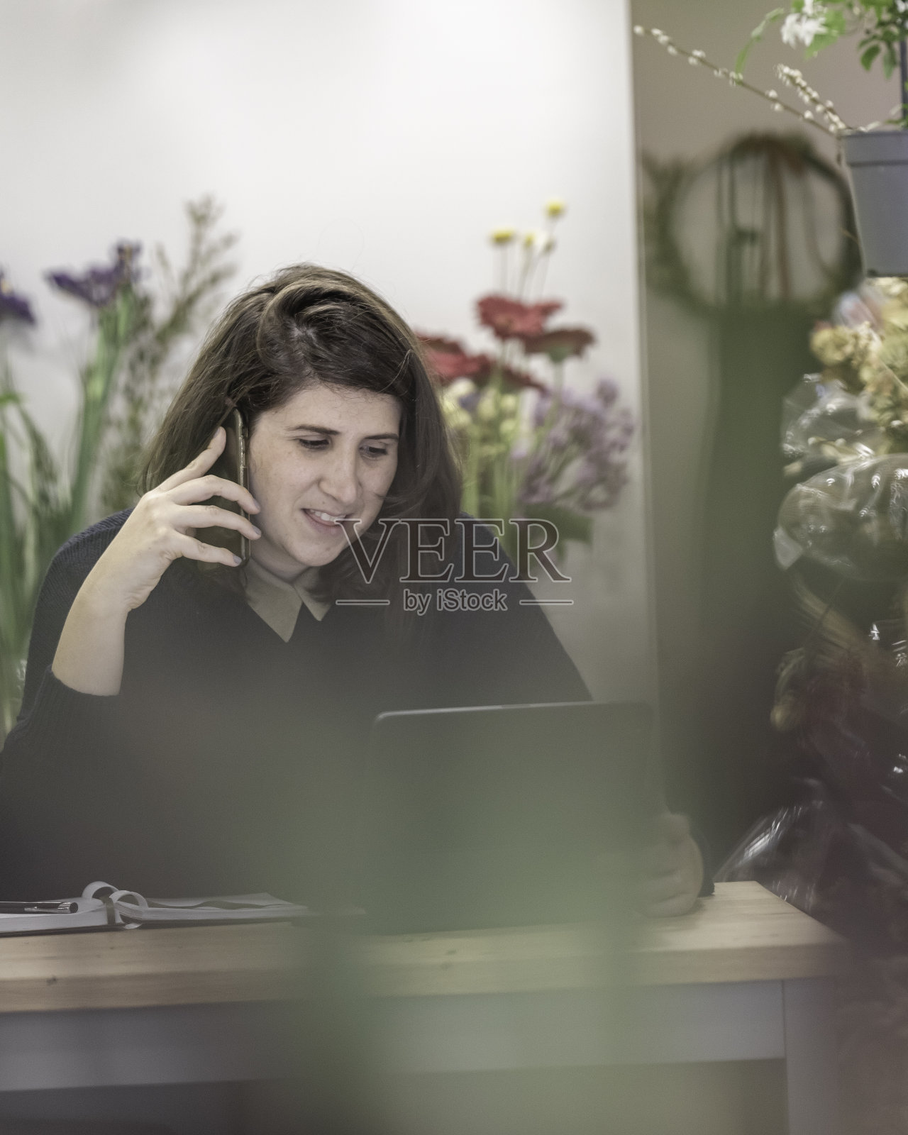 一个快乐的年轻女人作为花商工作日程安排会议前的一个小笔记本电脑，商业女性的概念。照片摄影图片