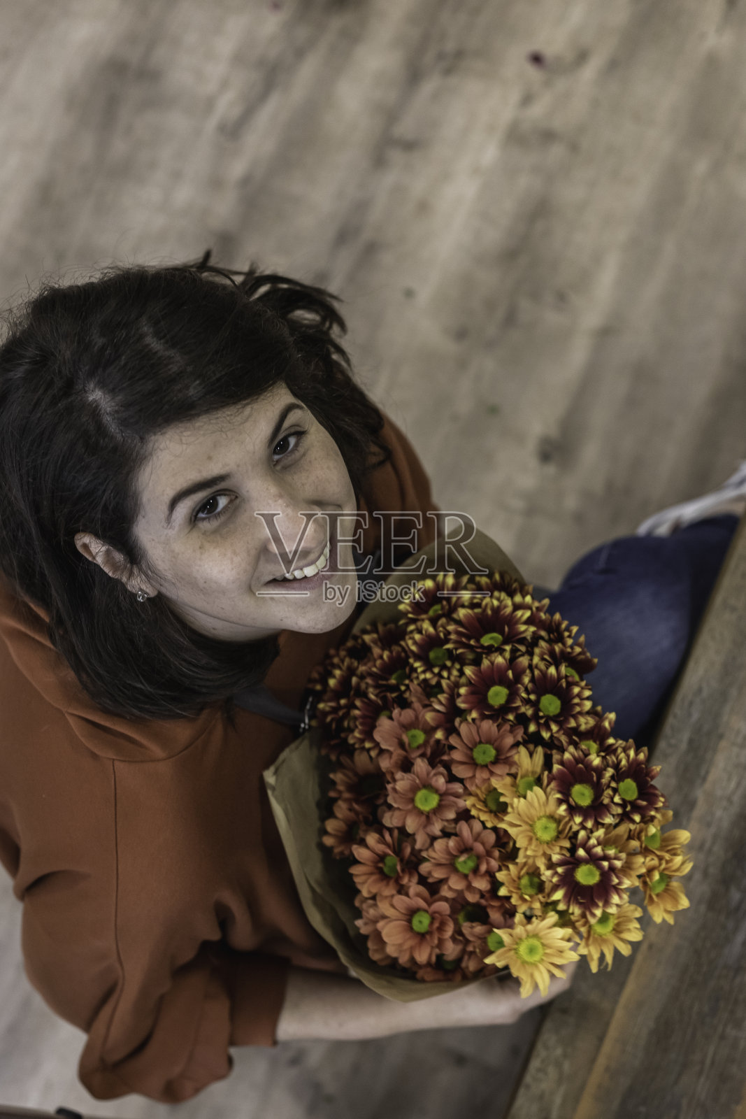 一个年轻的花商举着一束彩色的鲜花在花店的橱柜前的肖像。商人的概念。照片摄影图片