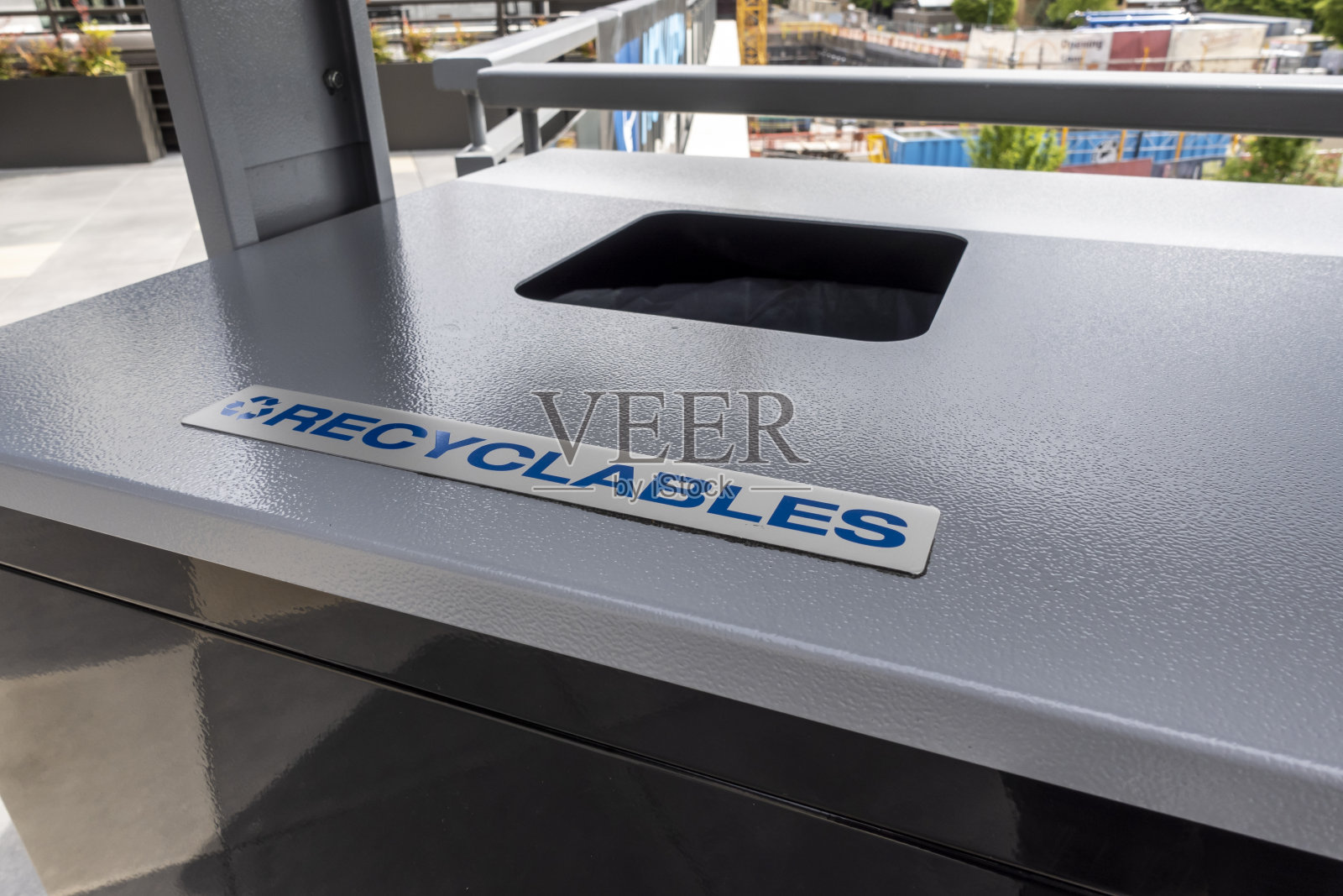 一个有盖的、灰色和黑色的户外垃圾桶，上面只贴着可回收物品的标签照片摄影图片