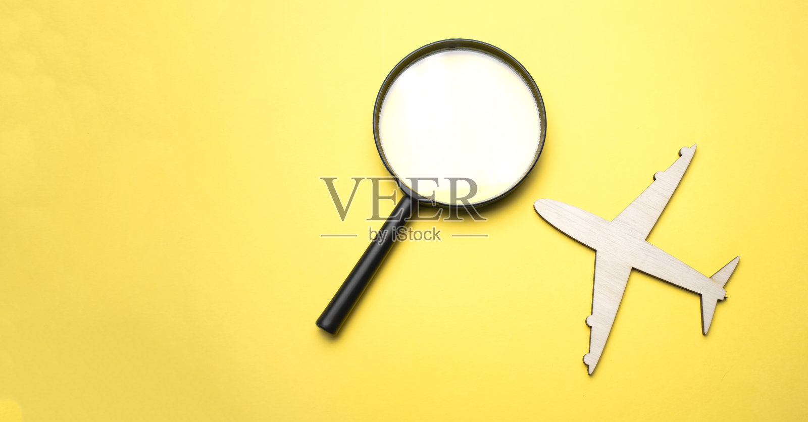 旅行的概念。飞机，带有黄色背景的地球仪放大镜。前视图。平躺照片摄影图片